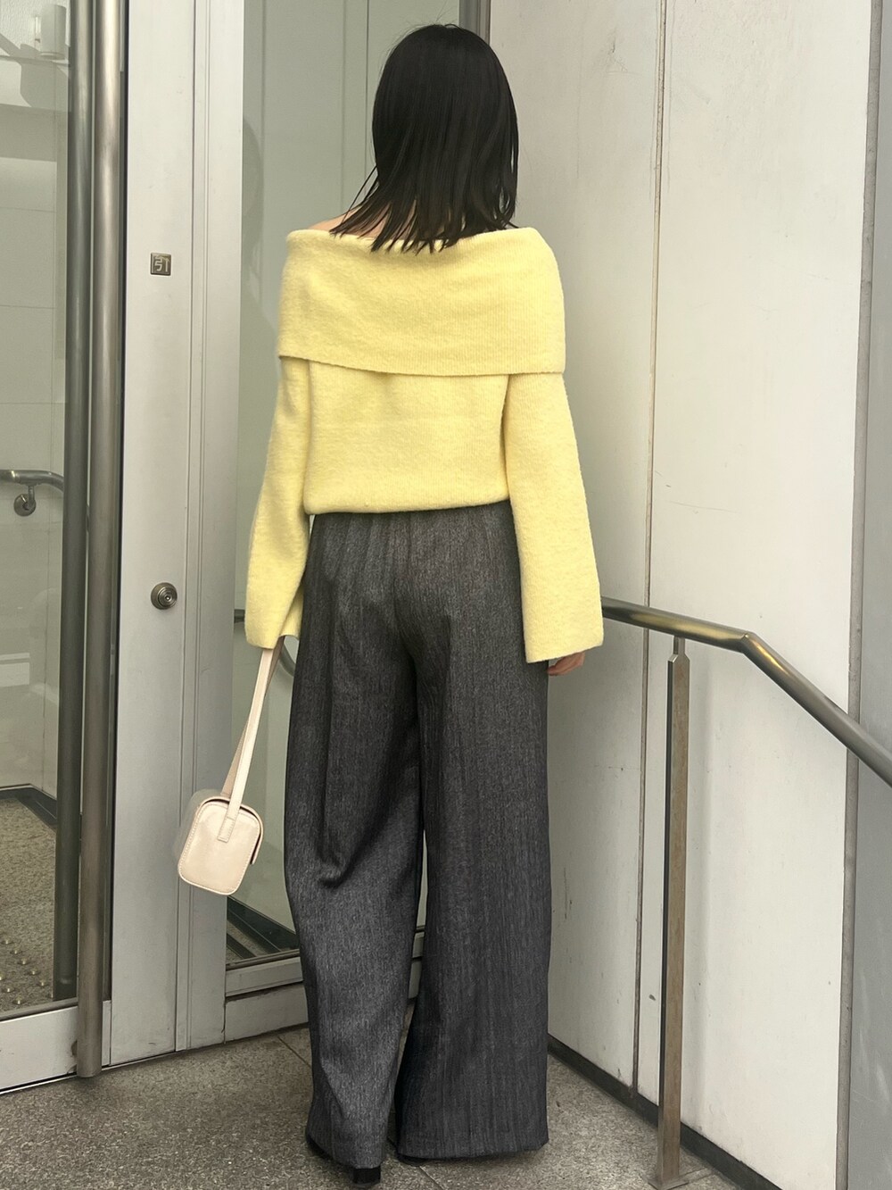 イエロー系のニット/セーター、ブラック系のブーツ、グレー系のその他パンツを着用したレディースの冬コーディネートの3枚目の写真