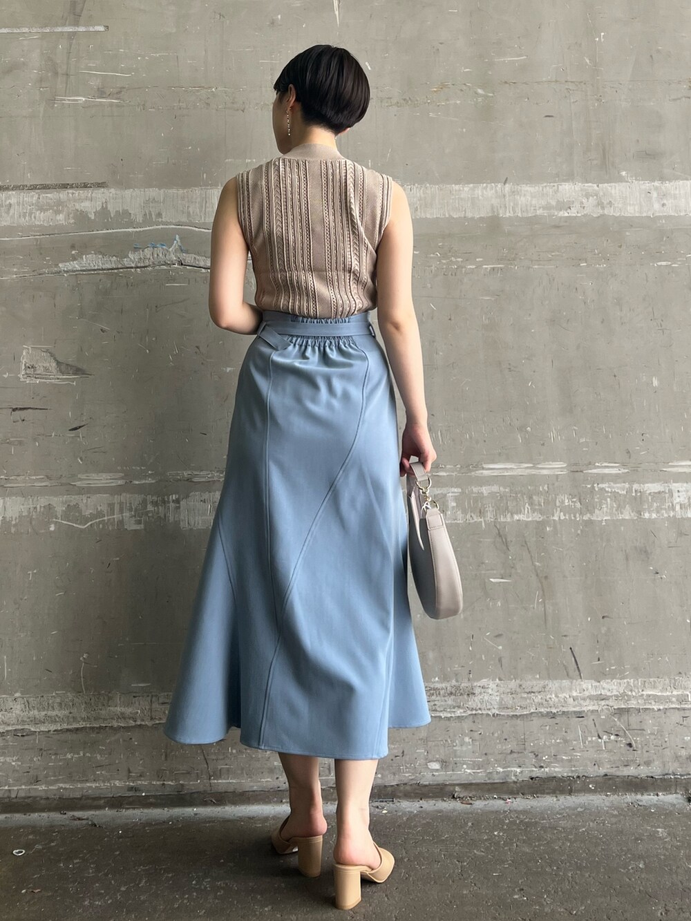 ベージュ系のニット/セーター、ブルー系のスカート、ベージュ系のサンダルを着用したレディースの夏コーディネートの2枚目の写真