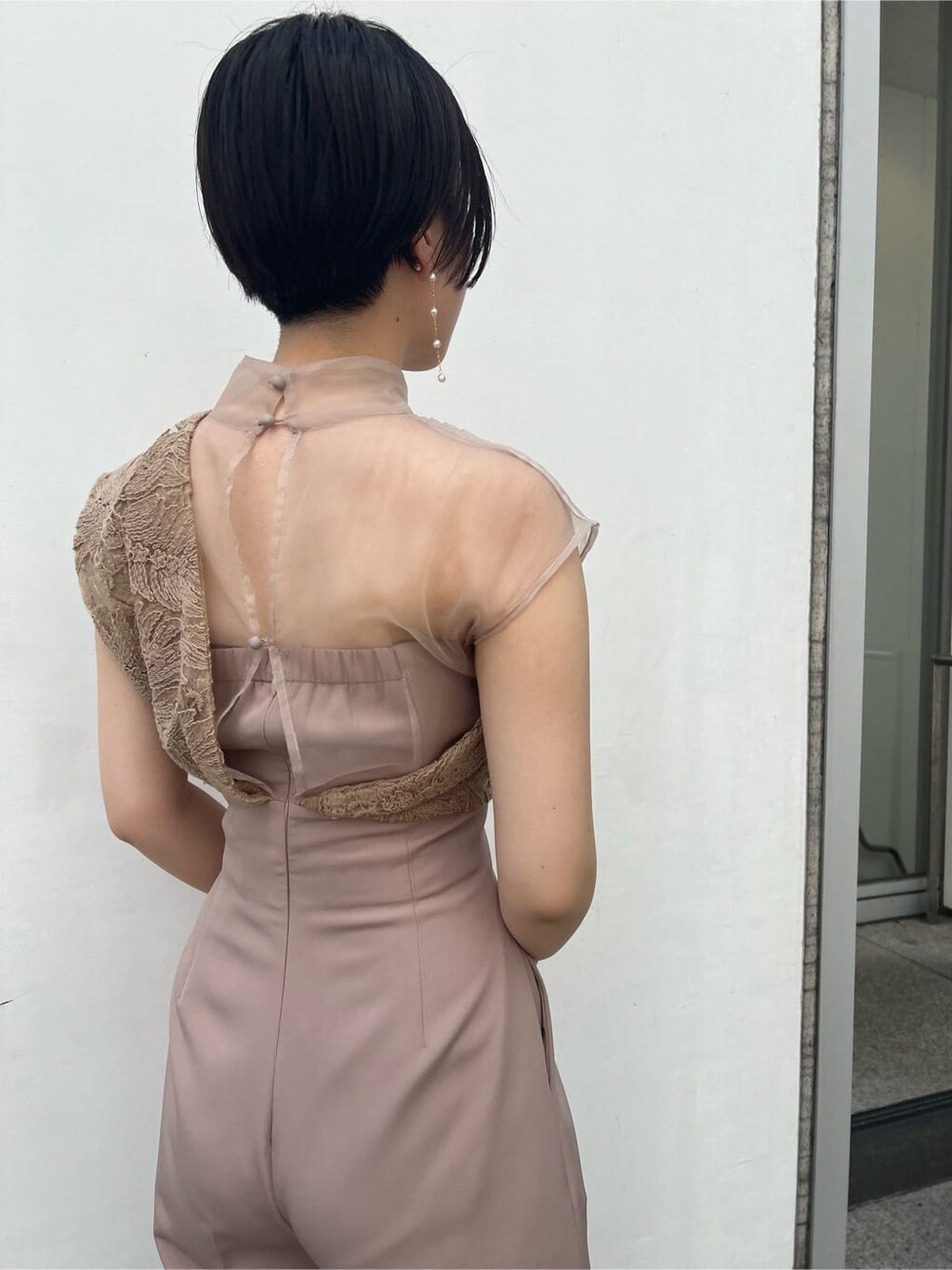 ゴールド系のクラッチバッグ、ベージュ系のパンツドレス、ブラック系のその他トップスを着用したレディースの夏コーディネートの7枚目の写真