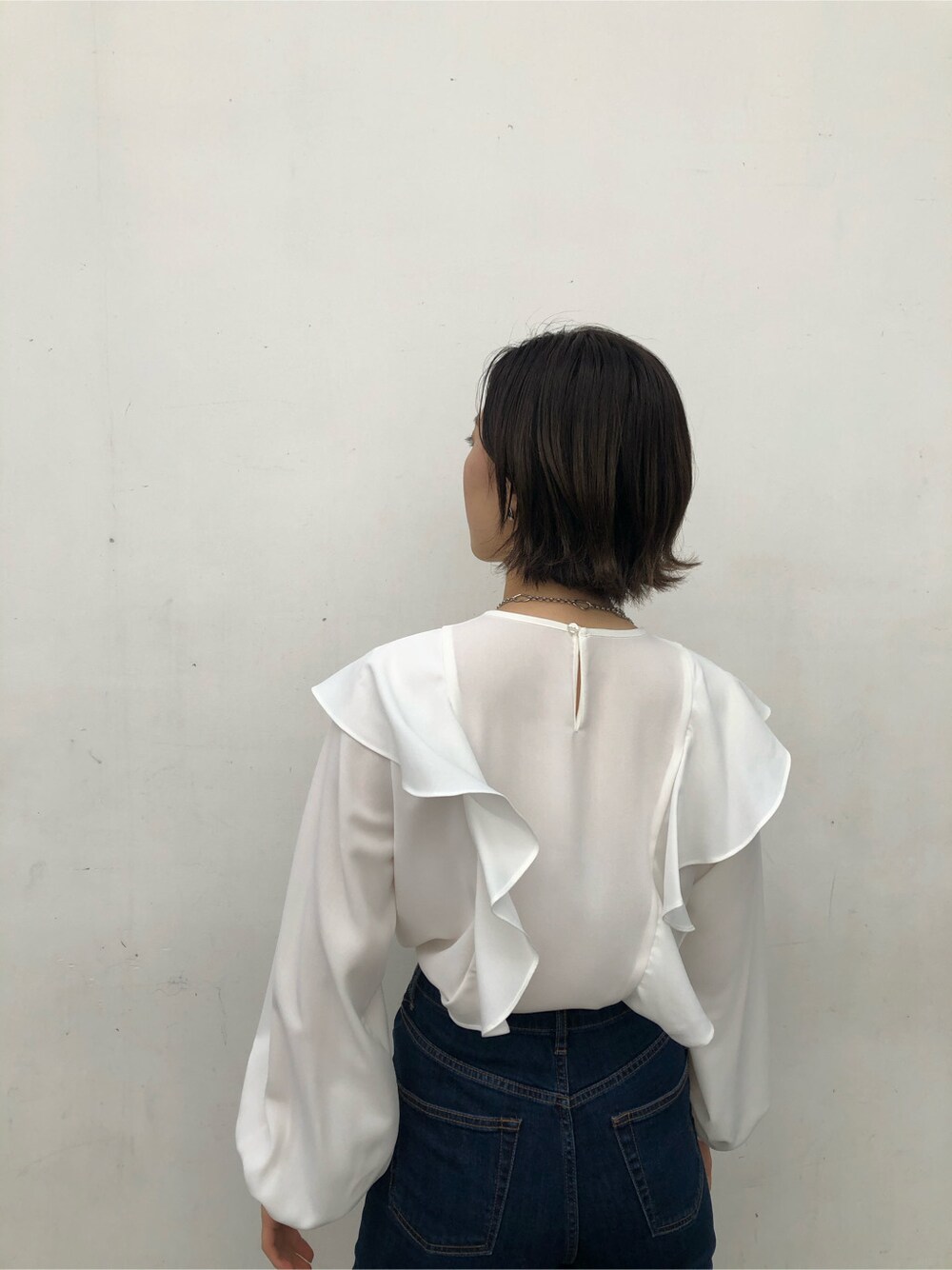 ブルー系のデニムパンツ、ブラック系のハンドバッグ、ブラウン系のパンプスを着用したレディースの春コーディネートの3枚目の写真