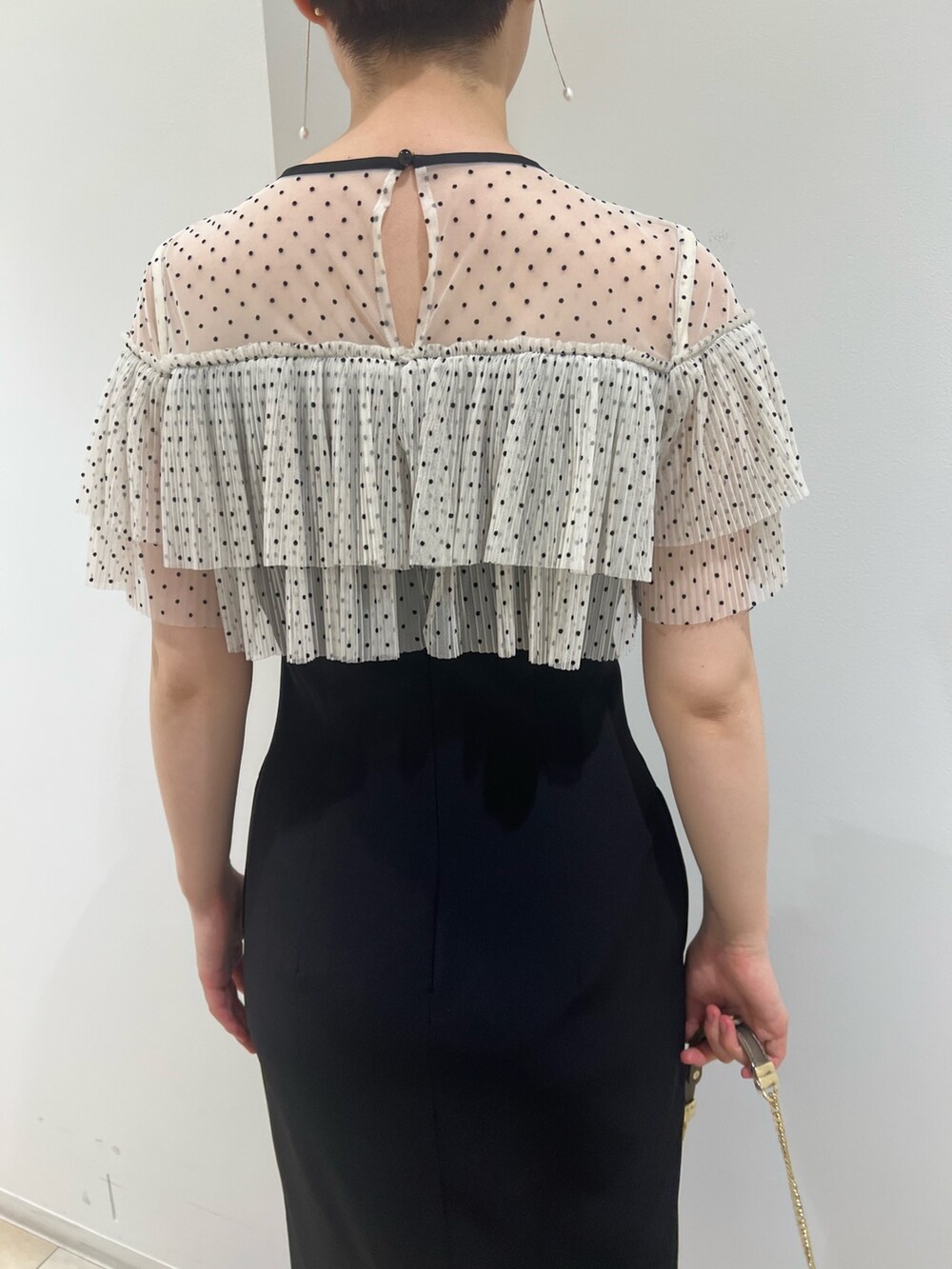 ゴールド系のパンプス、ゴールド系のハンドバッグ、ブラック系のドレスを着用したレディースの夏コーディネートの6枚目の写真