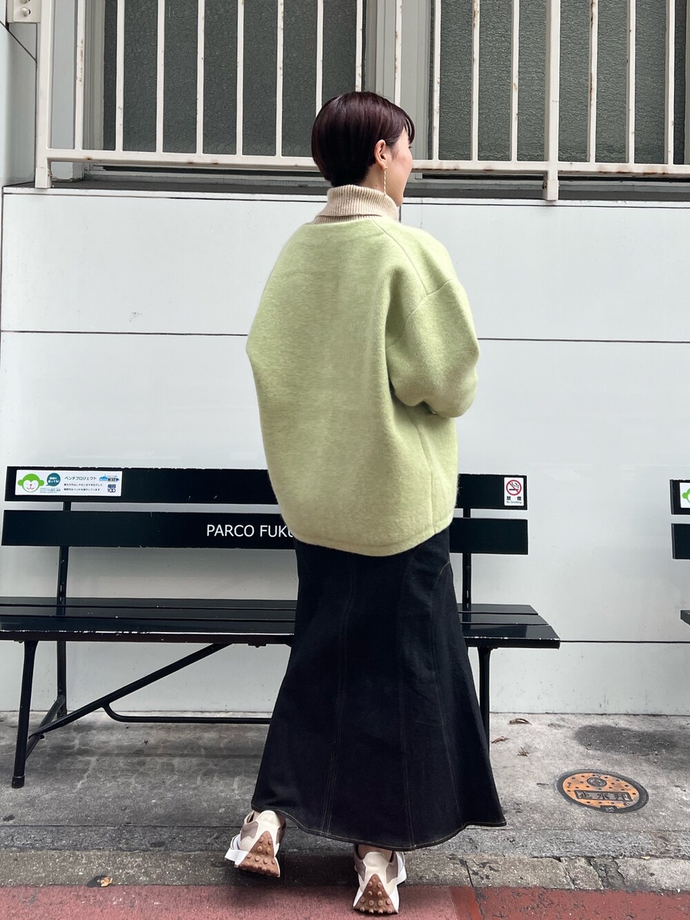 ベージュ系のスニーカー、グリーン系のカーディガン/ボレロ、ブラック系のデニムスカートを着用したレディースの秋コーディネートの2枚目の写真