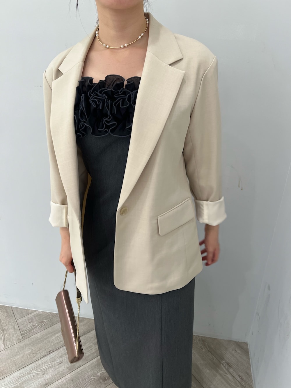 ゴールド系のパンプス、グレー系のドレス、ベージュ系のテーラードジャケットを着用したレディースの秋コーディネートの4枚目の写真