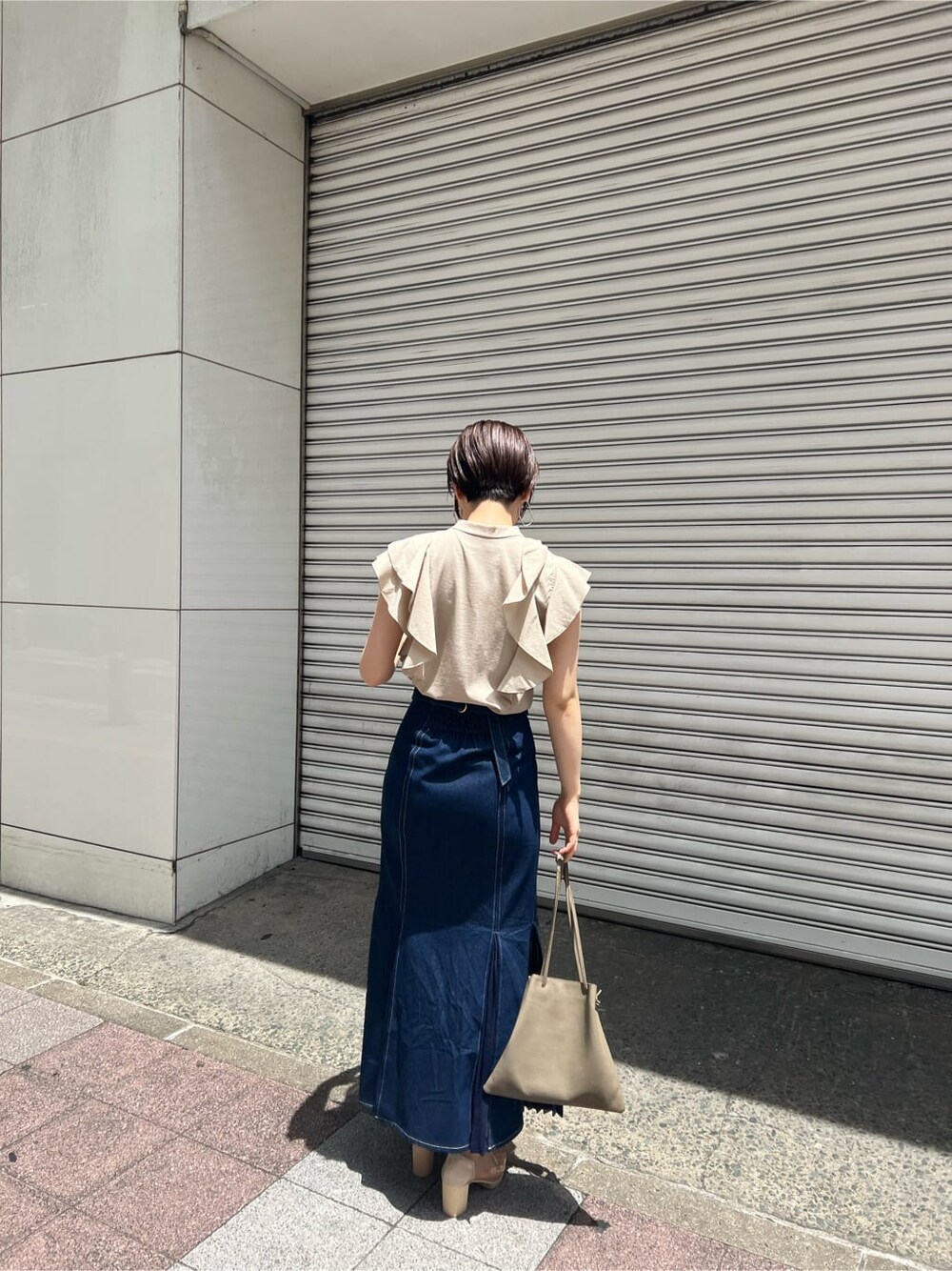 ベージュ系のハンドバッグ、ブルー系のスカート、その他のパンプスを着用したレディースの春コーディネートの3枚目の写真
