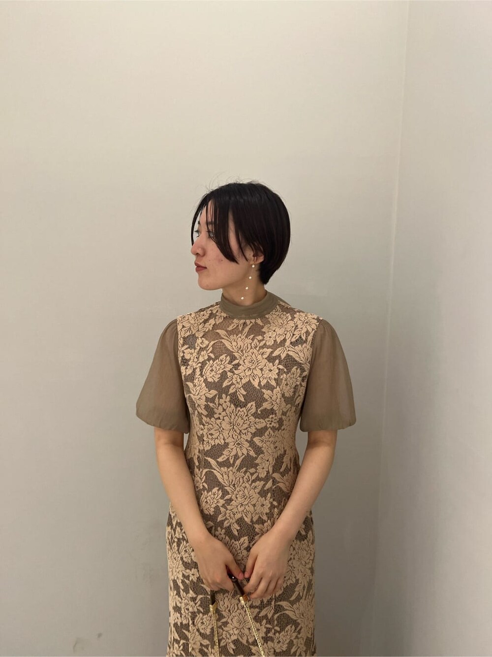 ゴールド系のクラッチバッグ、ゴールド系のパンプス、ベージュ系のドレスを着用したレディースの夏コーディネートの4枚目の写真