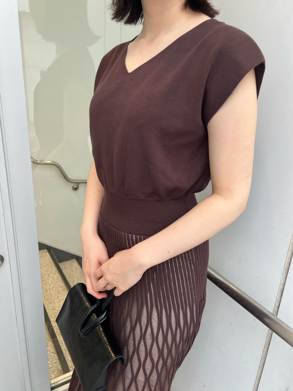 ブラック系のサンダル、ブラック系のハンドバッグ、ブラウン系のワンピースを着用したレディースの夏コーディネートの6枚目の写真