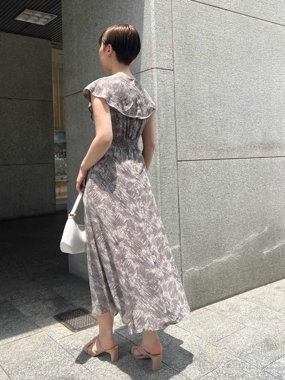 ホワイト系のハンドバッグ、ベージュ系のサンダル、グレー系のワンピースを着用したレディースの夏コーディネートの2枚目の写真