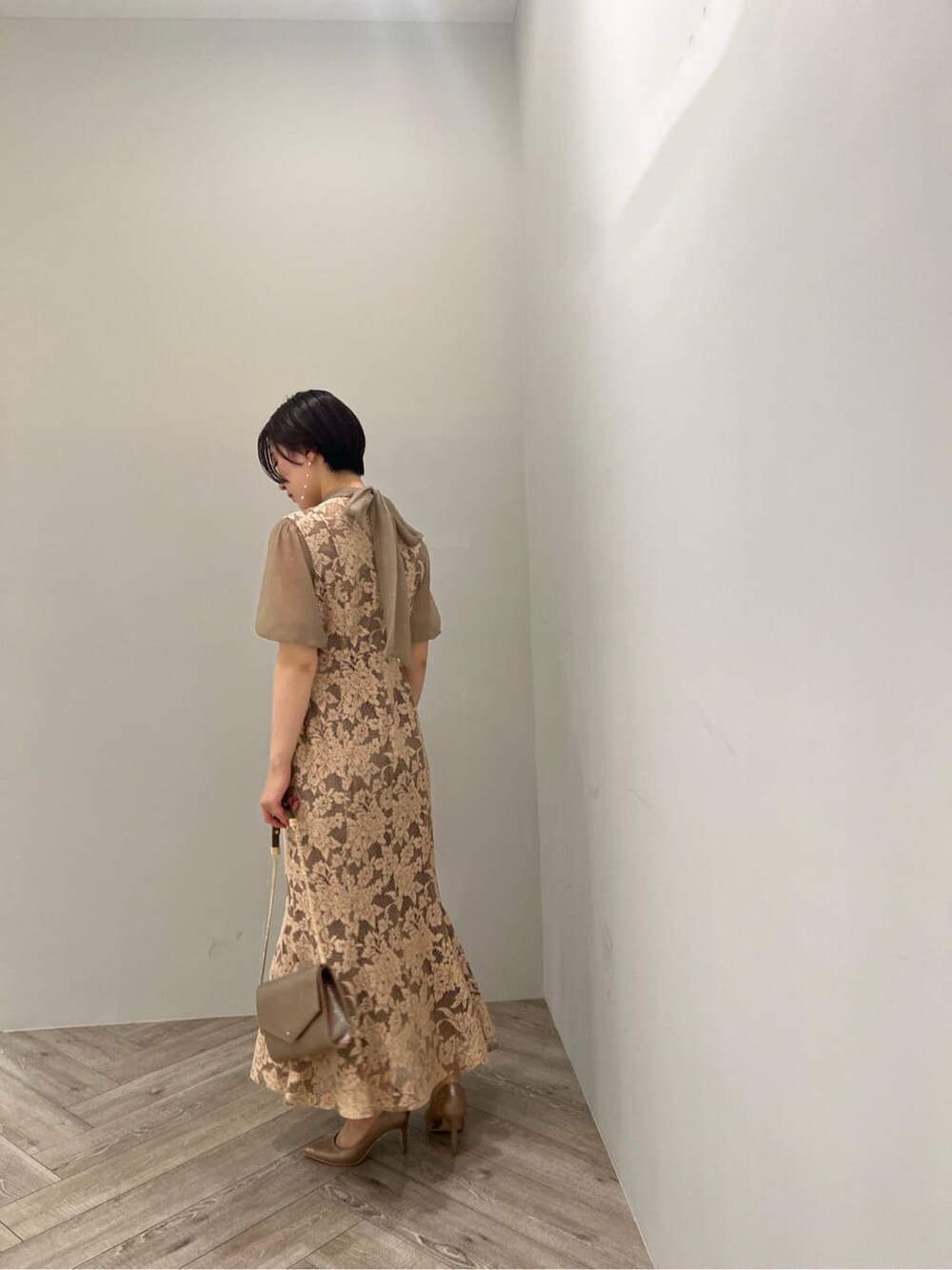 ゴールド系のクラッチバッグ、ゴールド系のパンプス、ベージュ系のドレスを着用したレディースの夏コーディネートの2枚目の写真