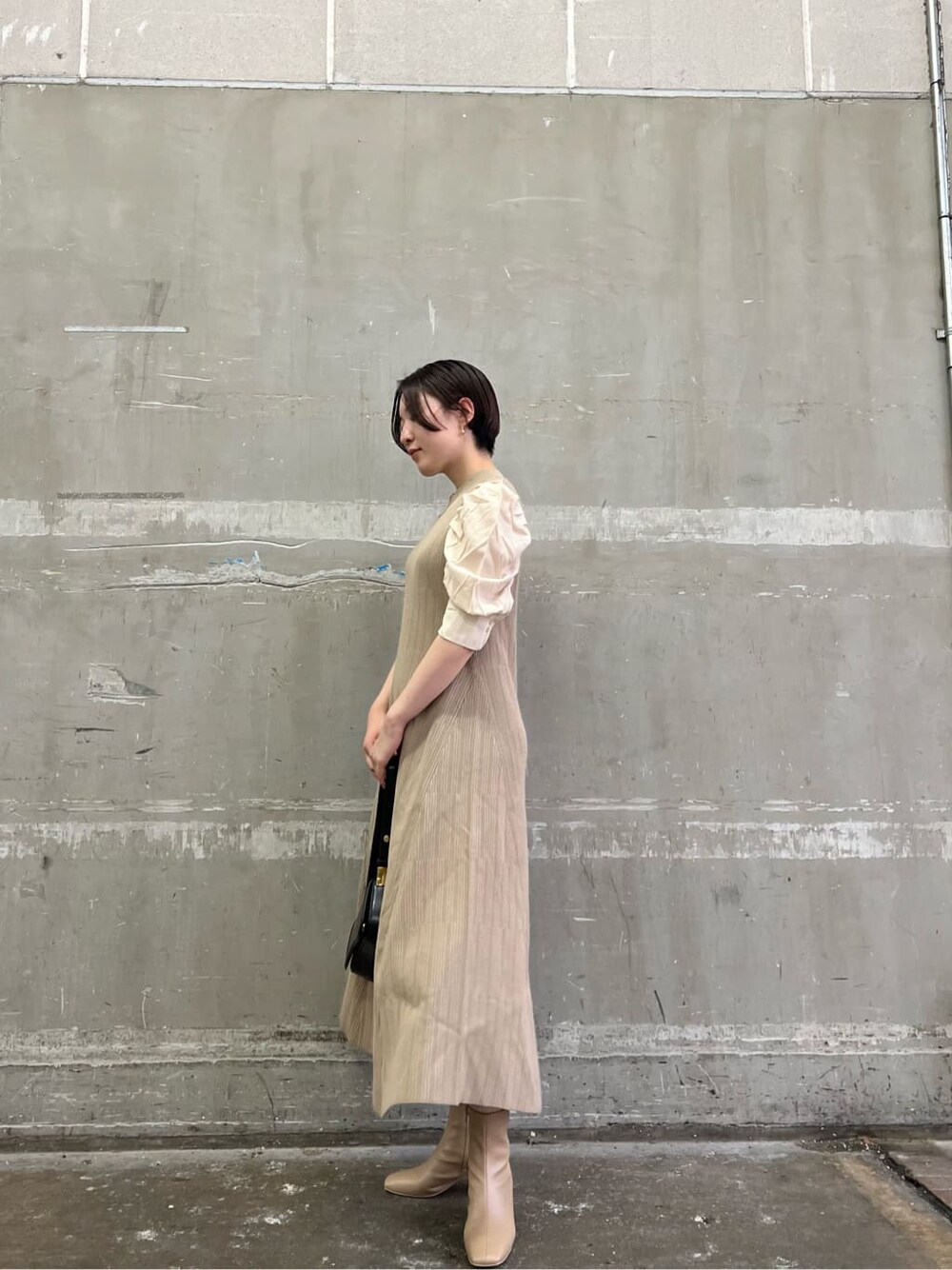 ベージュ系のワンピース、ベージュ系のブーツ、ブラック系のショルダーバッグを着用したレディースの夏コーディネートの2枚目の写真