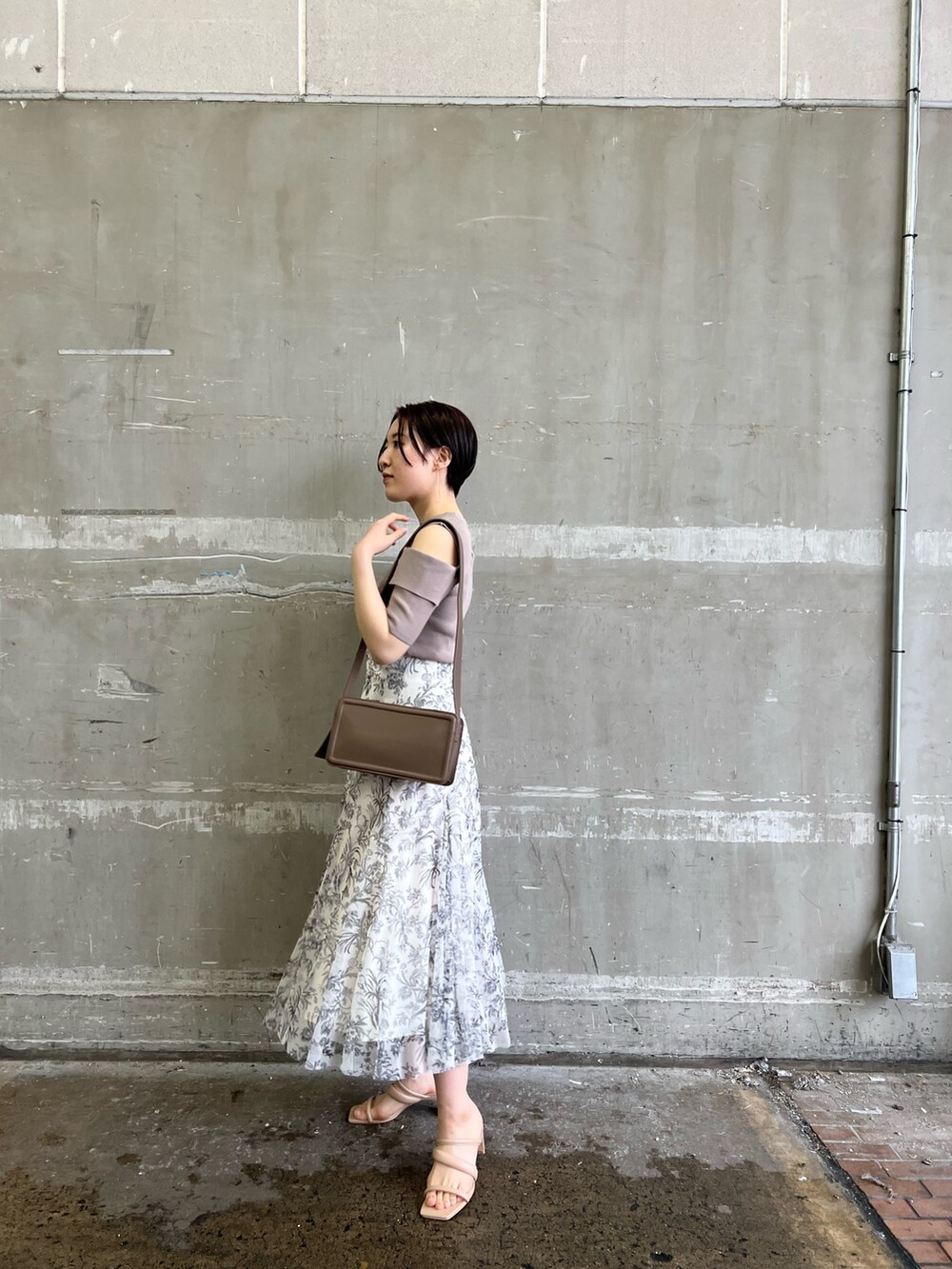 ベージュ系のノーカラーコート、ホワイト系のスカート、ベージュ系のサンダルを着用したレディースの冬コーディネートの6枚目の写真