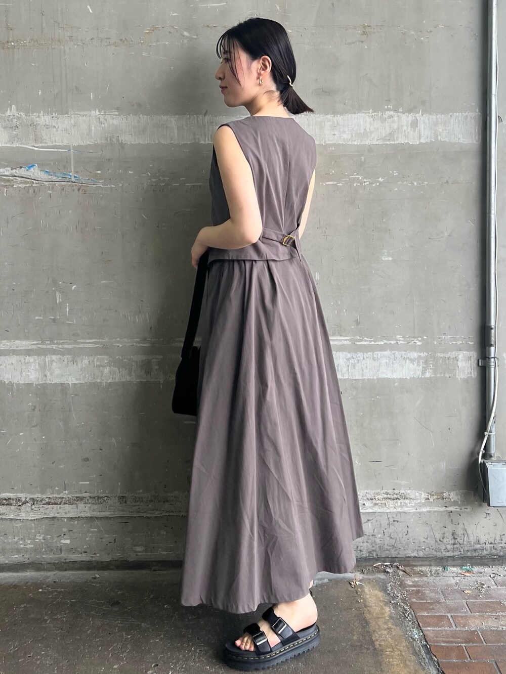 グレー系のワンピース、ブラック系のハンドバッグ、ブラック系のサンダルを着用したレディースの夏コーディネートの2枚目の写真