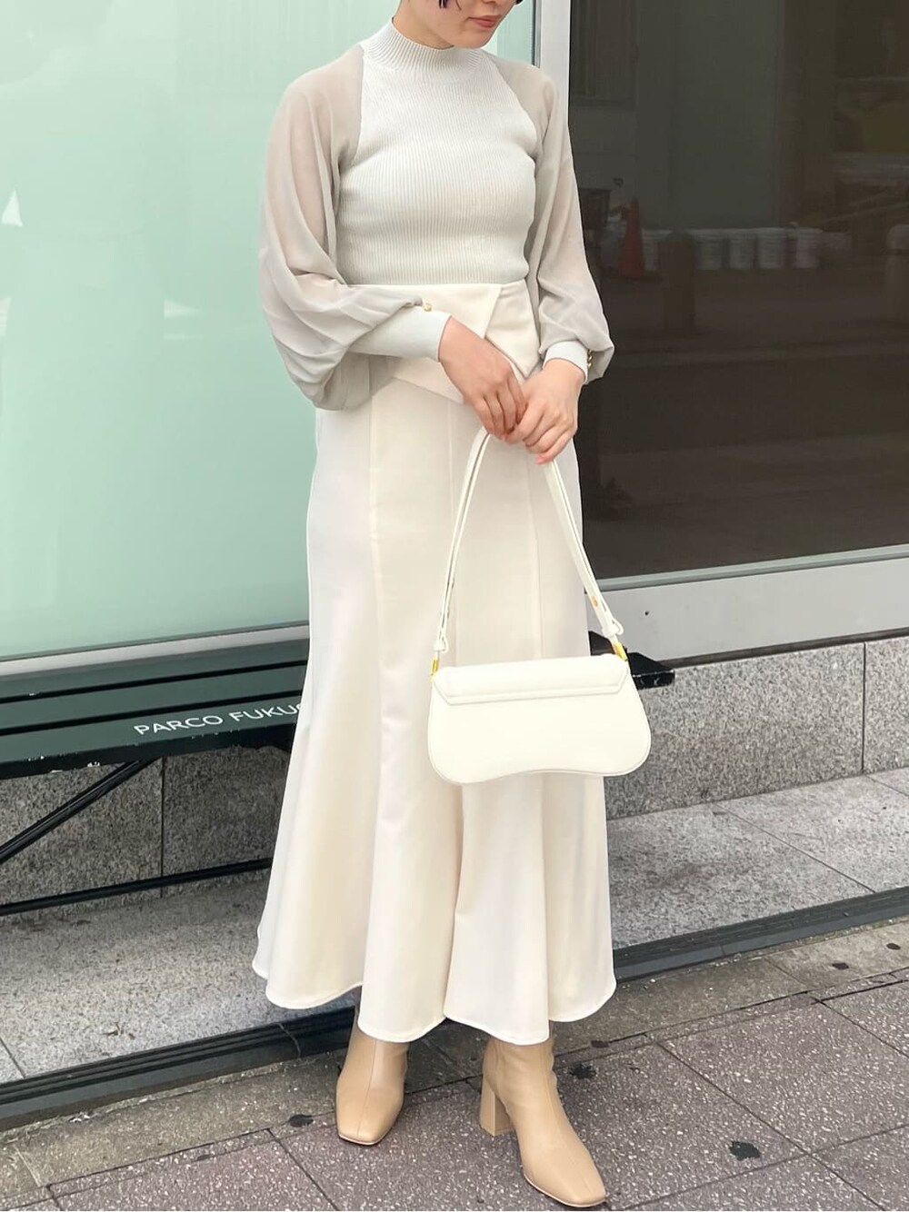 ベージュ系のブーツ、ブラック系のその他トップス、ホワイト系のスカートを着用したレディースの夏コーディネートの3枚目の写真