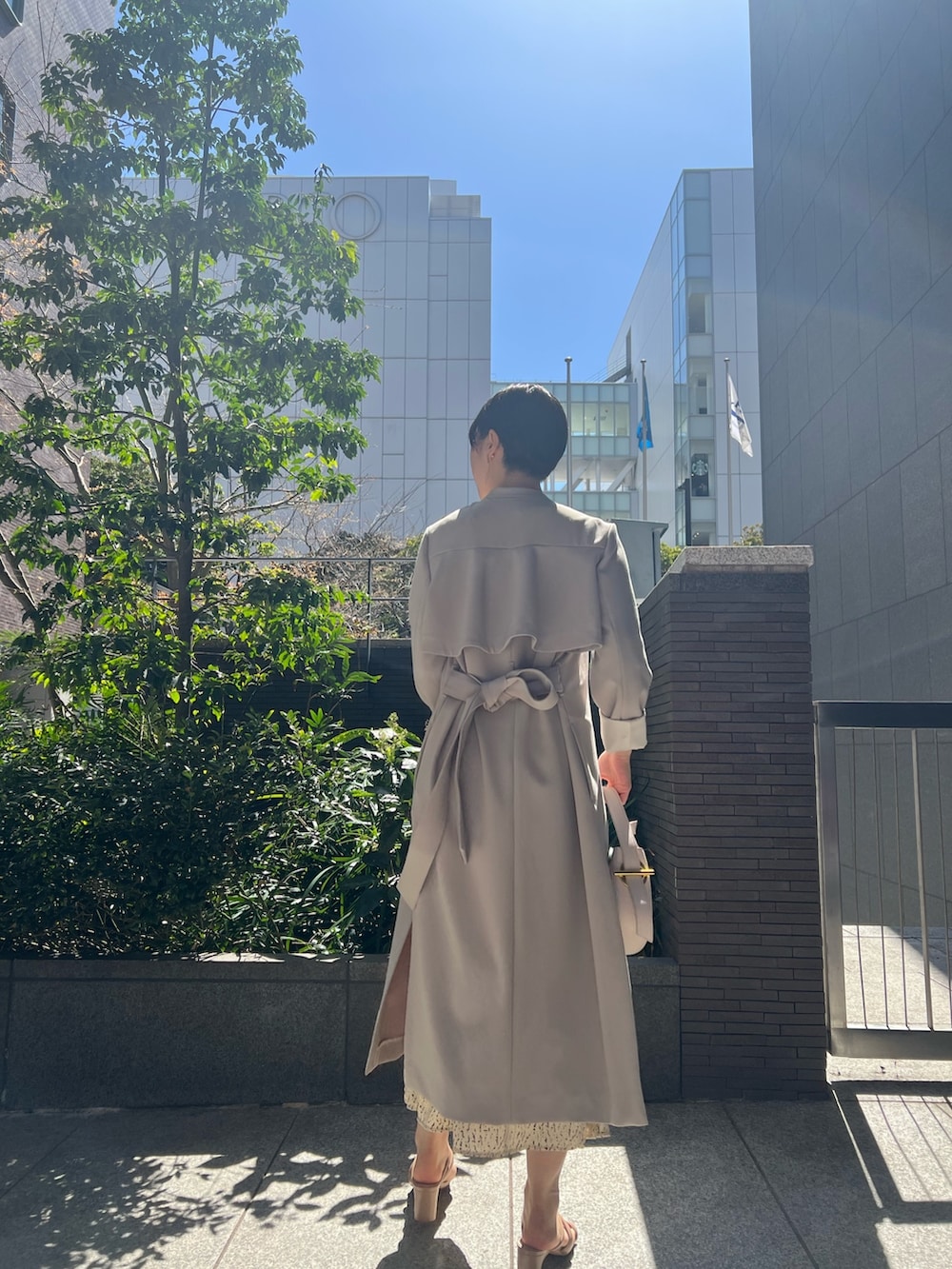 ホワイト系のハンドバッグ、ベージュ系のサンダル、ホワイト系のワンピースを着用したレディースの春コーディネートの2枚目の写真