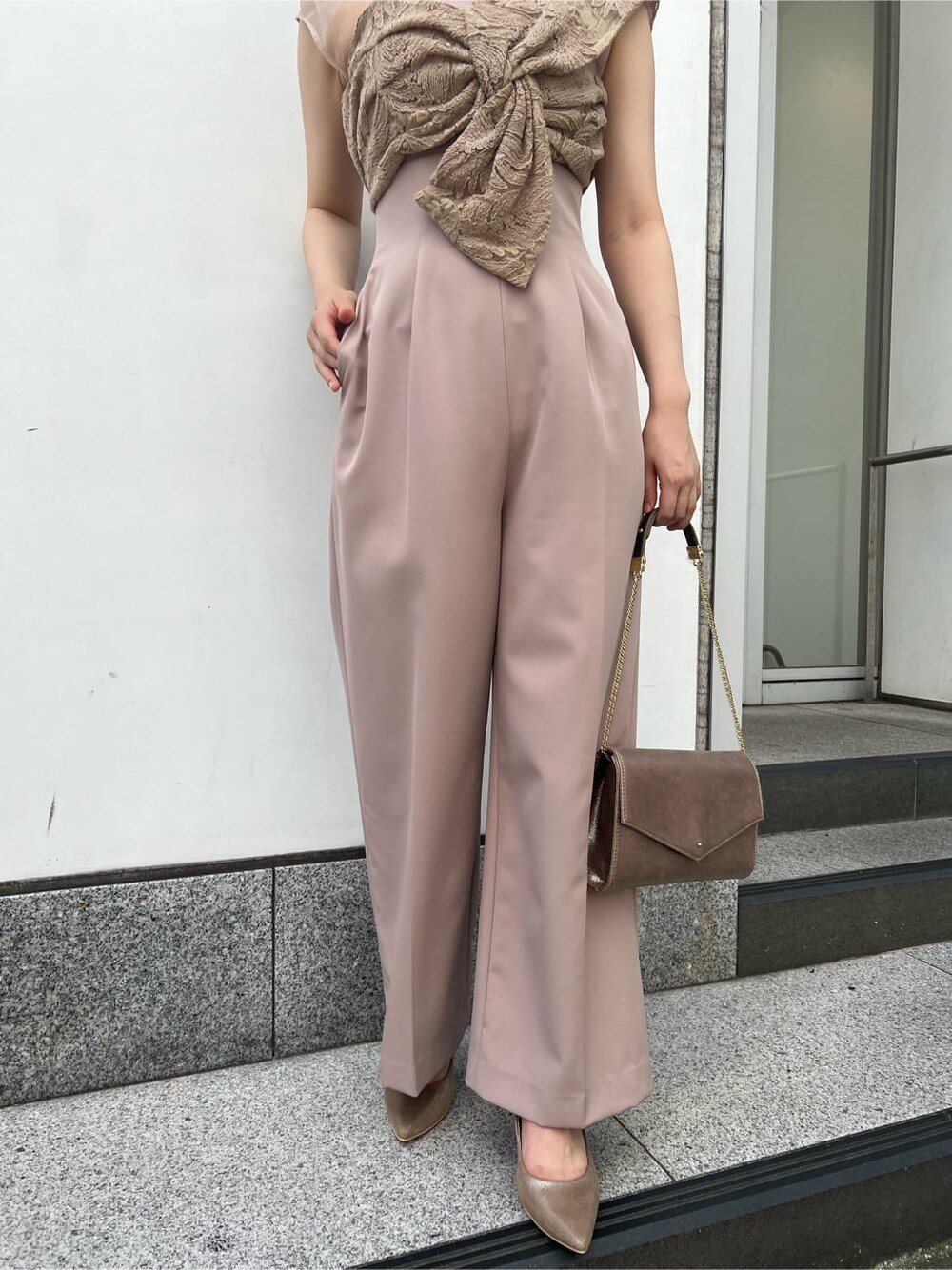 ゴールド系のクラッチバッグ、ベージュ系のパンツドレス、ブラック系のその他トップスを着用したレディースの夏コーディネートの8枚目の写真