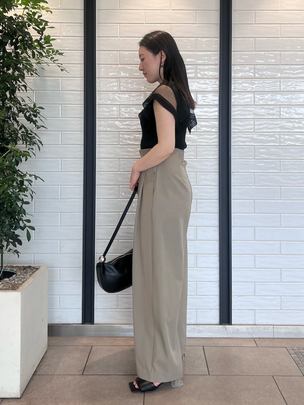 ブラウン系のその他パンツ、ブラック系のニット/セーター、ブラック系のサンダルを着用したレディースの春コーディネートの2枚目の写真