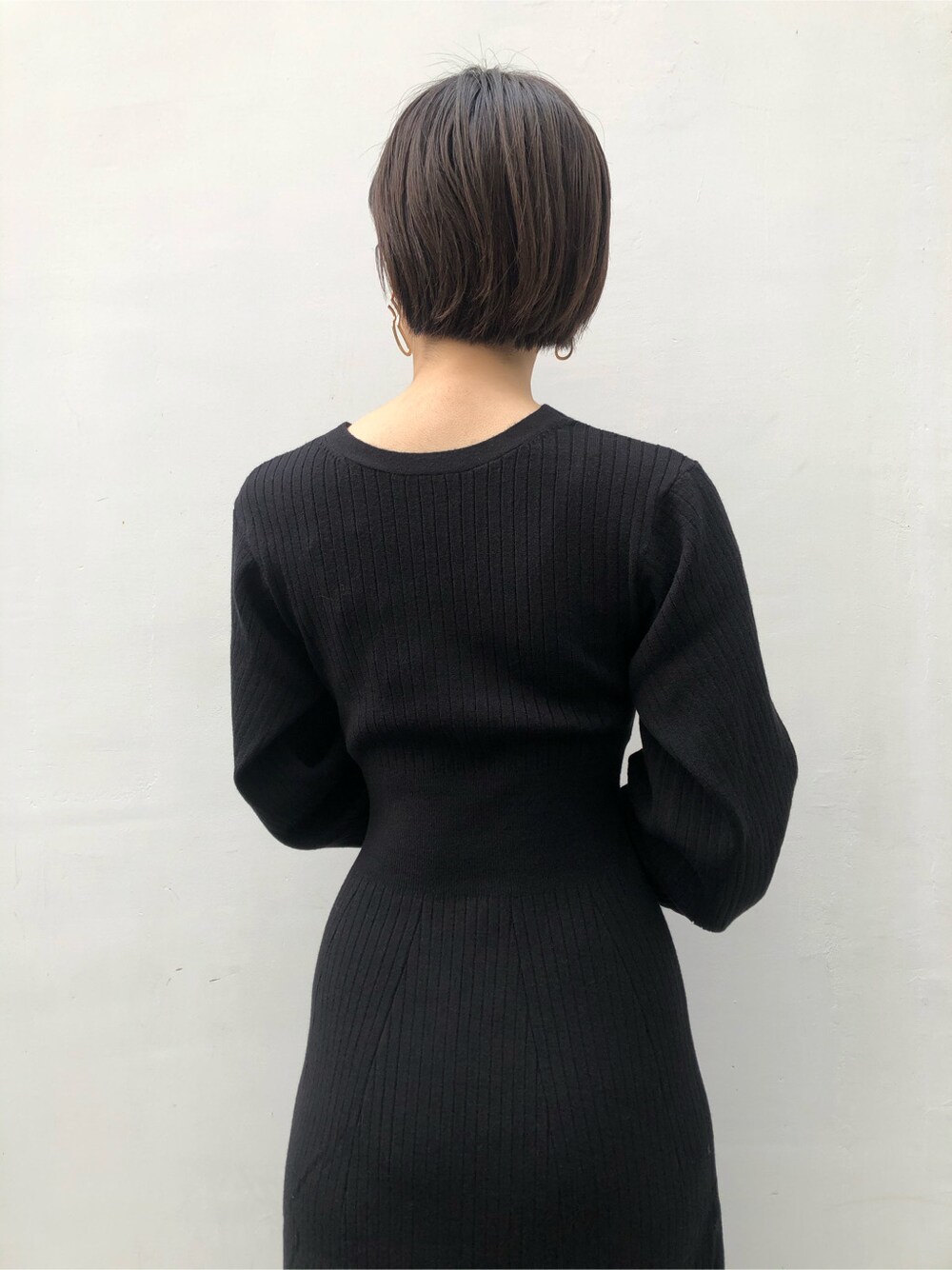 ブラック系のワンピース、ゴールド系のピアス（両耳用）を着用したレディースの冬コーディネートの6枚目の写真