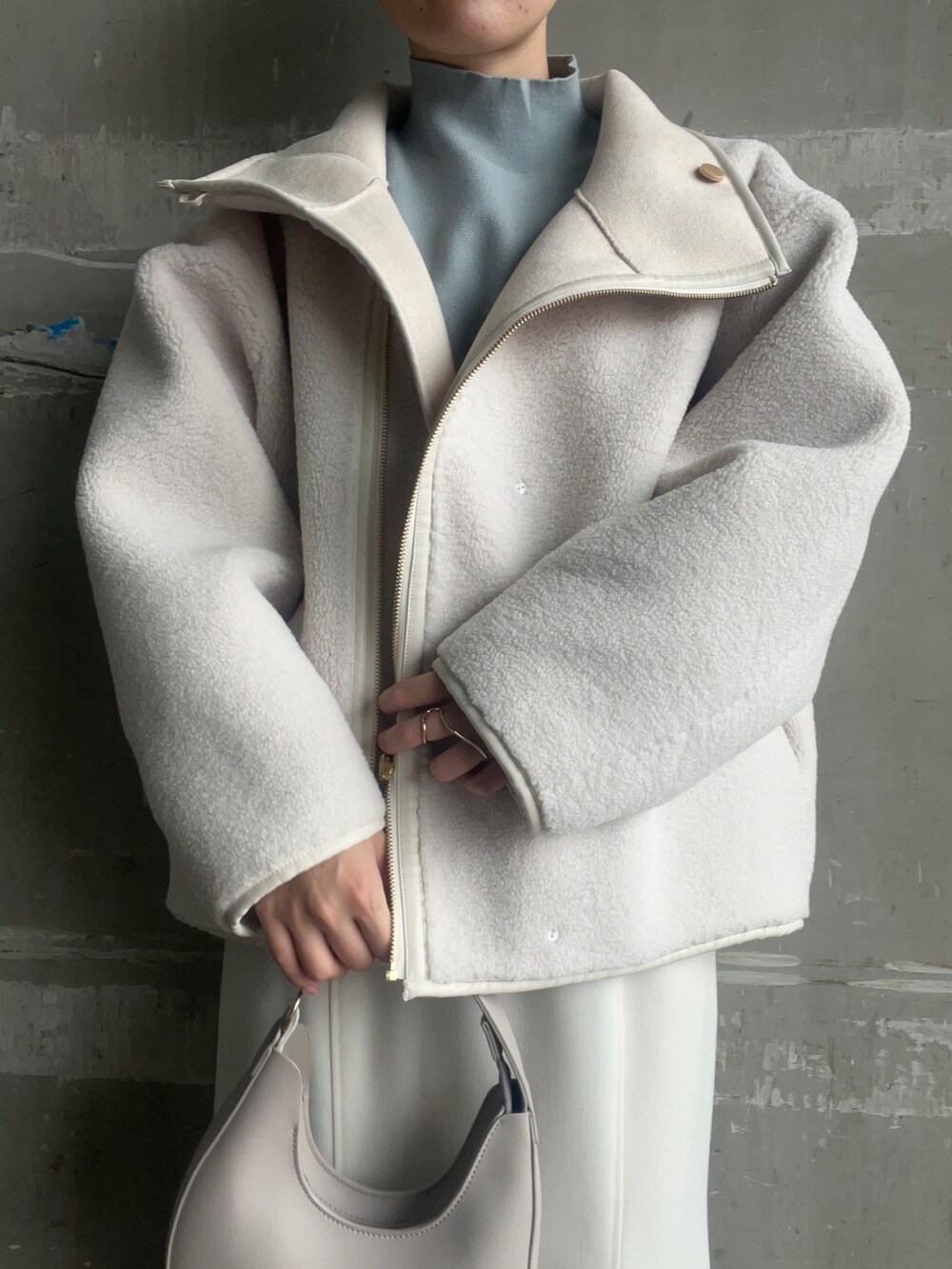 ベージュ系のブーツ、ホワイト系のハンドバッグ、ホワイト系のムートンコートを着用したレディースの秋コーディネートの4枚目の写真