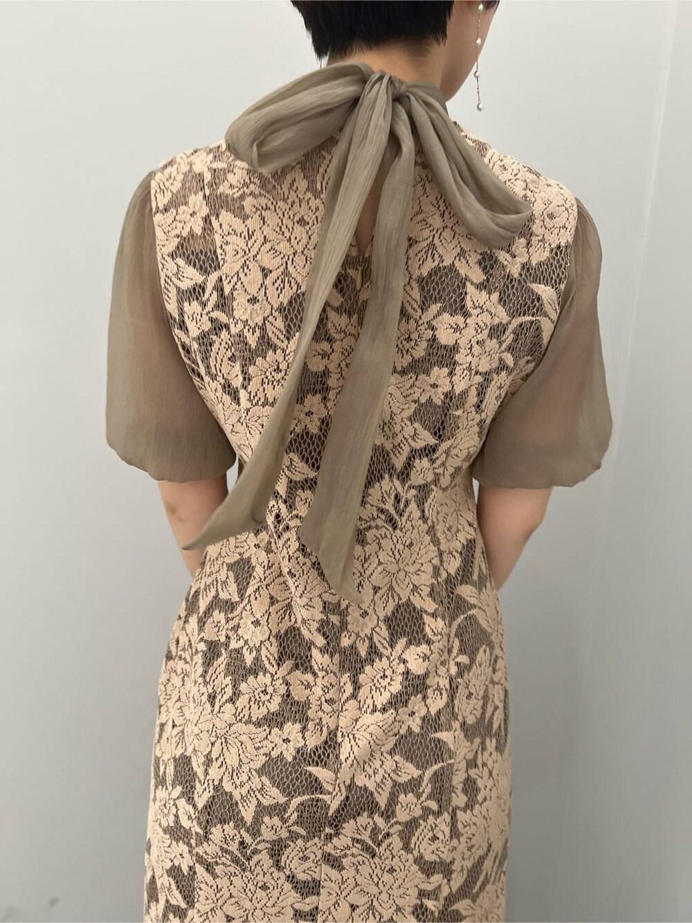 ゴールド系のクラッチバッグ、ゴールド系のパンプス、ベージュ系のドレスを着用したレディースの夏コーディネートの6枚目の写真