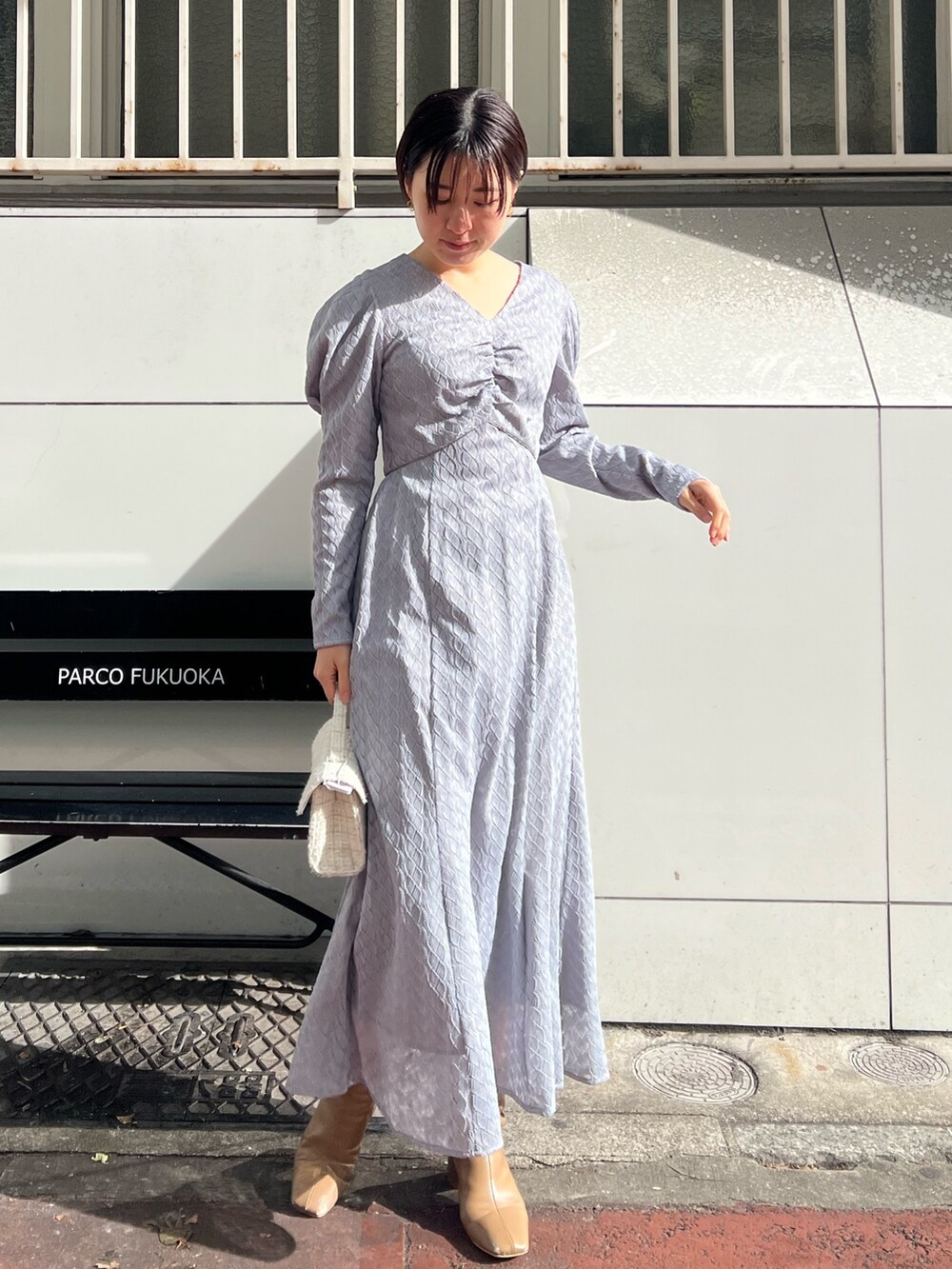 ホワイト系のショルダーバッグ、ベージュ系のブーツ、ベージュ系のその他アウターを着用したレディースの冬コーディネートの6枚目の写真