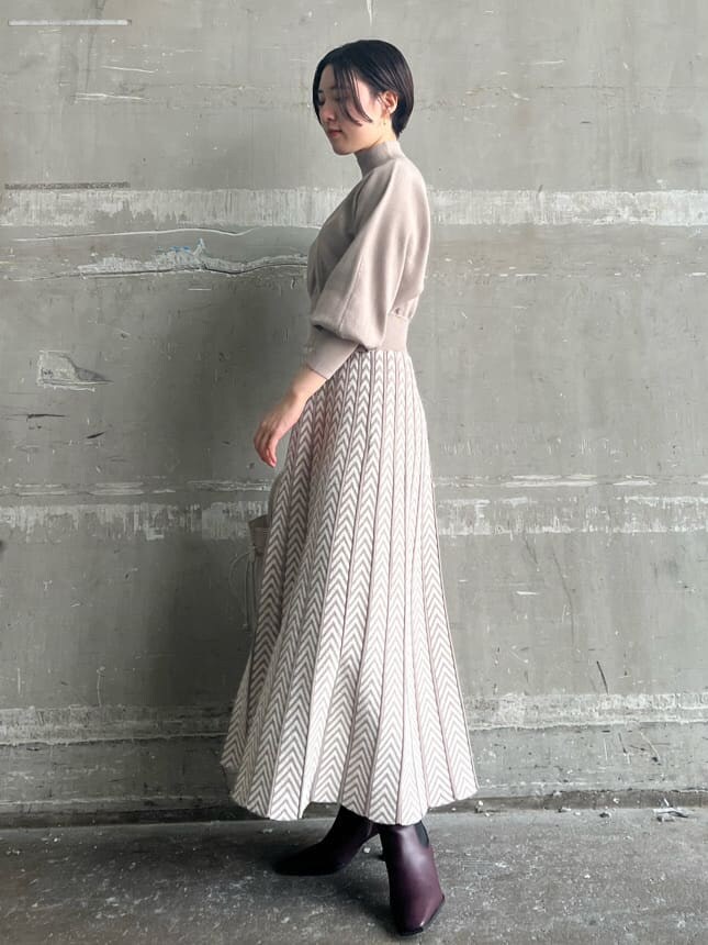 レッド系のブーツ、ベージュ系のワンピース、ホワイト系のハンドバッグを着用したレディースの秋コーディネートの7枚目の写真