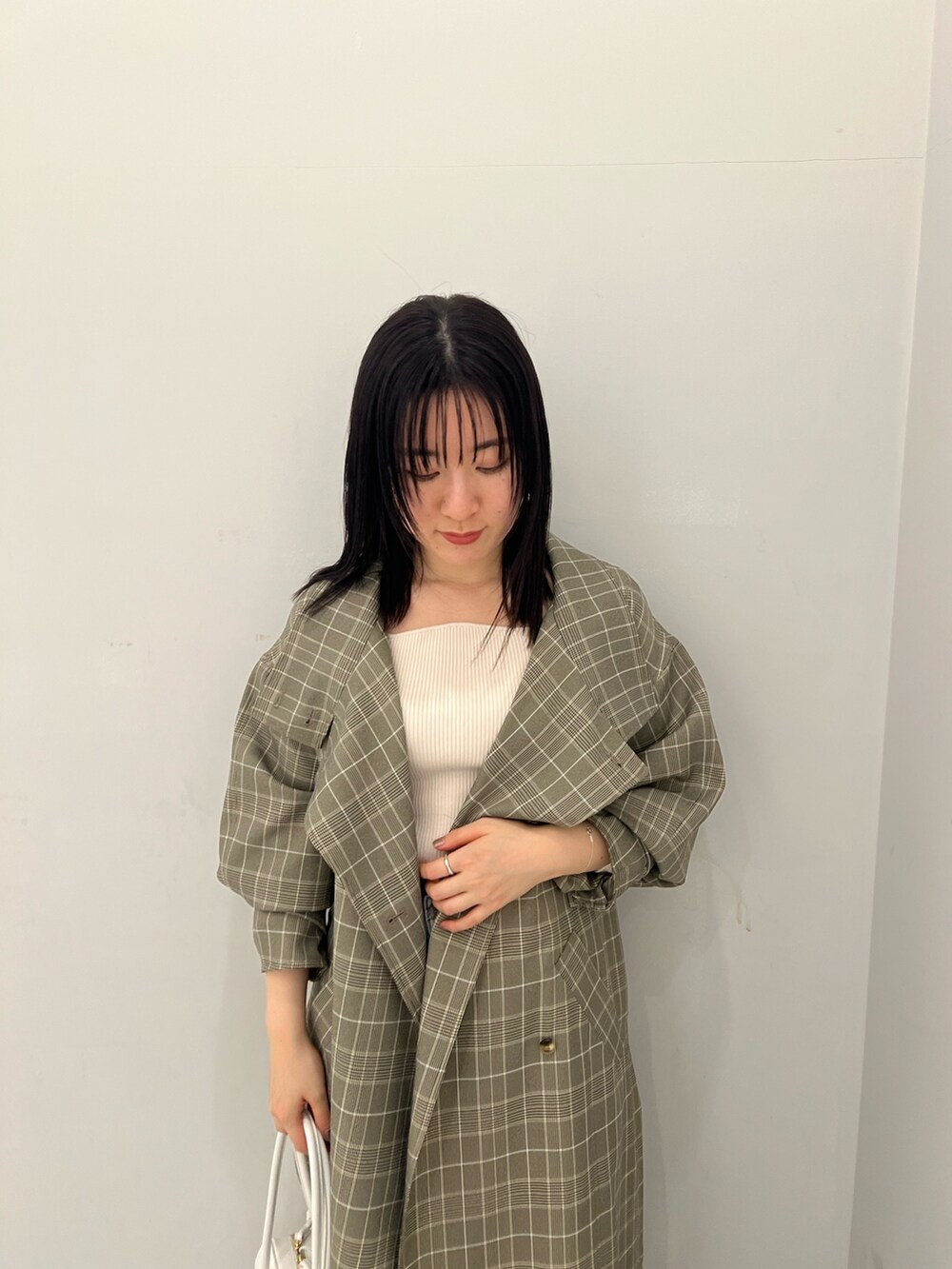 グレー系のチェスターコート、ブルー系のデニムパンツ、ホワイト系のニット/セーターを着用したレディースの春コーディネートの3枚目の写真