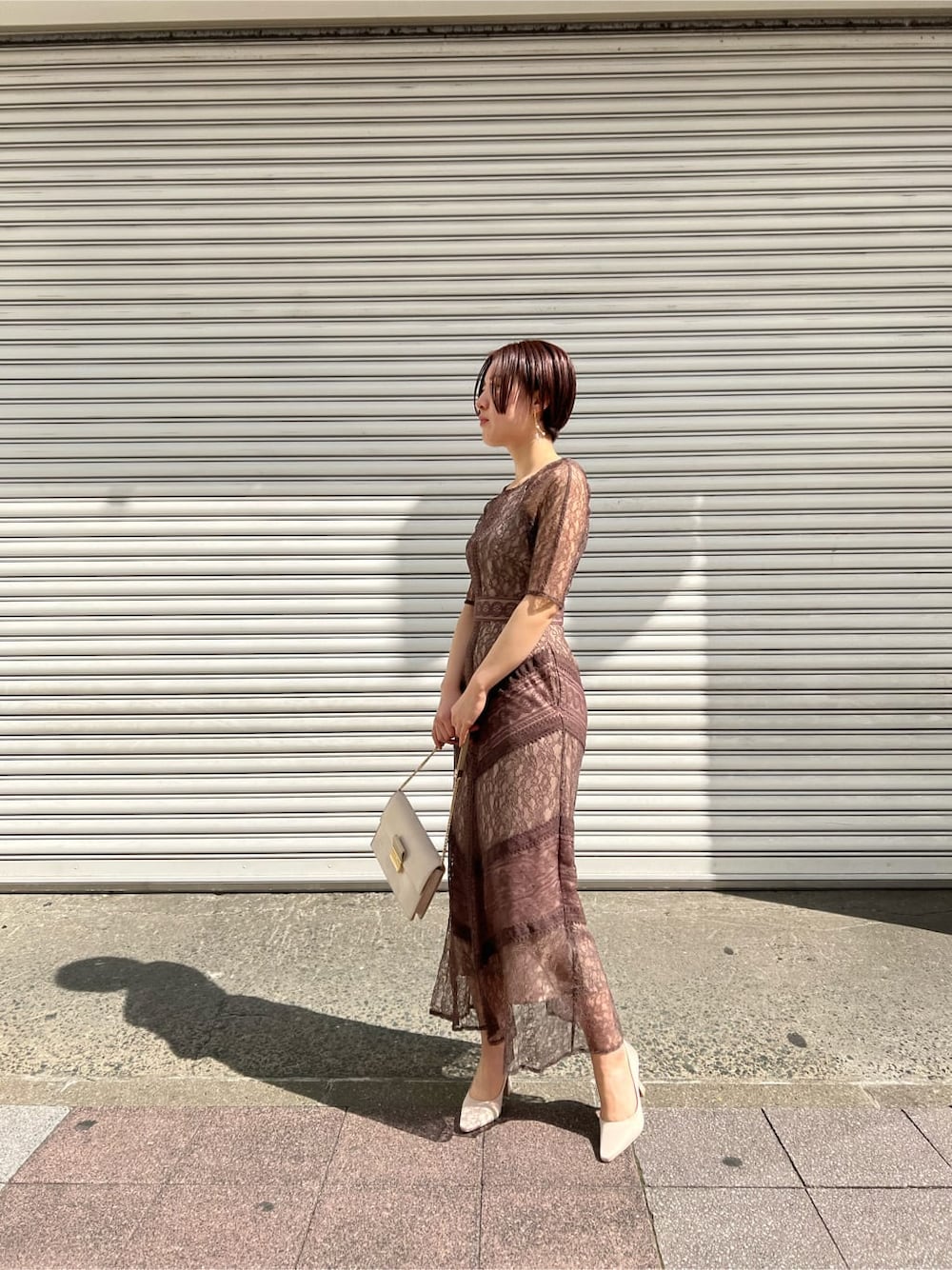 ホワイト系のノーカラーコート、ベージュ系のドレス、ベージュ系のクラッチバッグを着用したレディースの春コーディネートの2枚目の写真