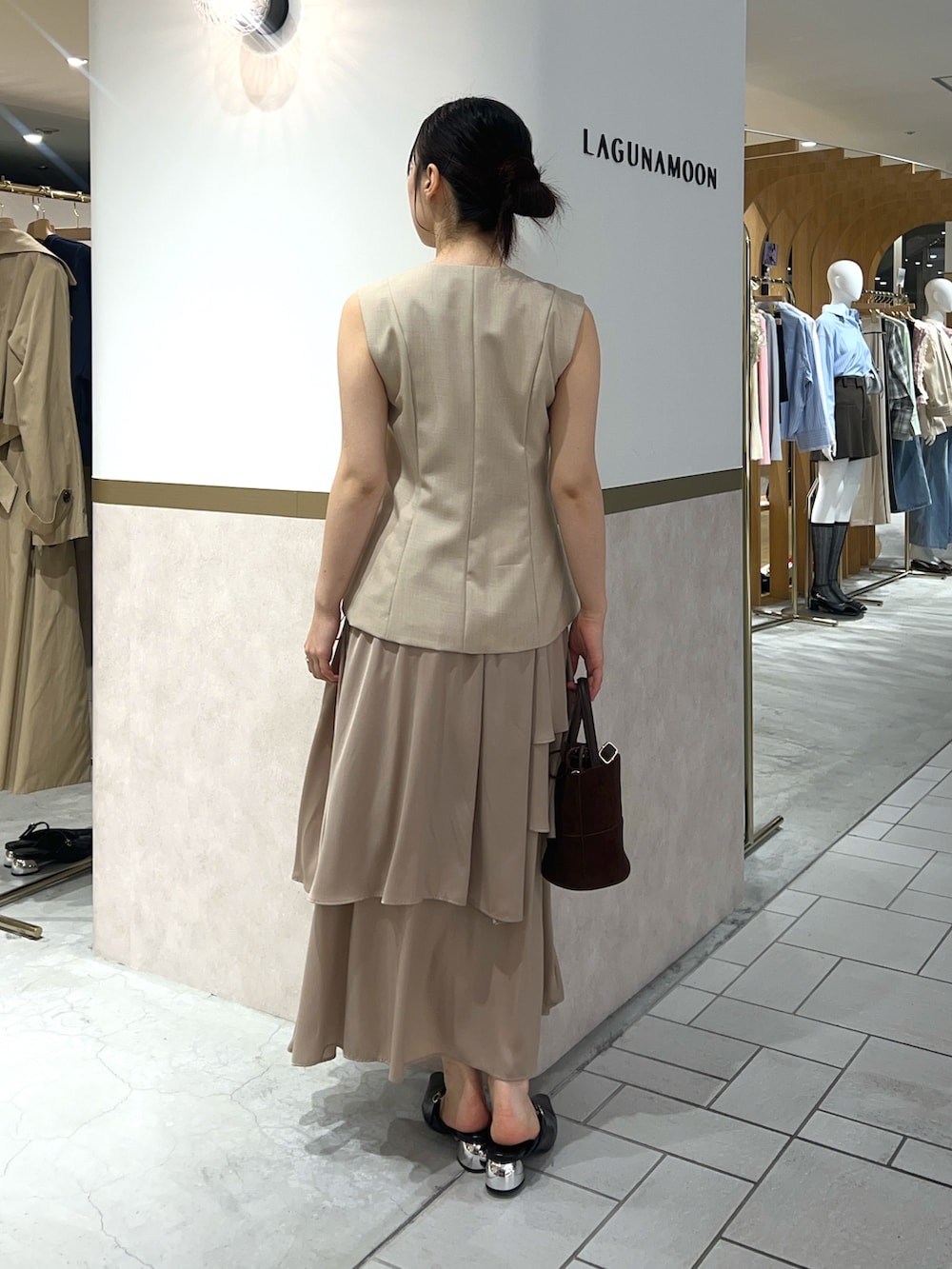 ベージュ系のワンピース、ブラック系のパンプス、ブラウン系のハンドバッグを着用したレディースの春コーディネートの3枚目の写真