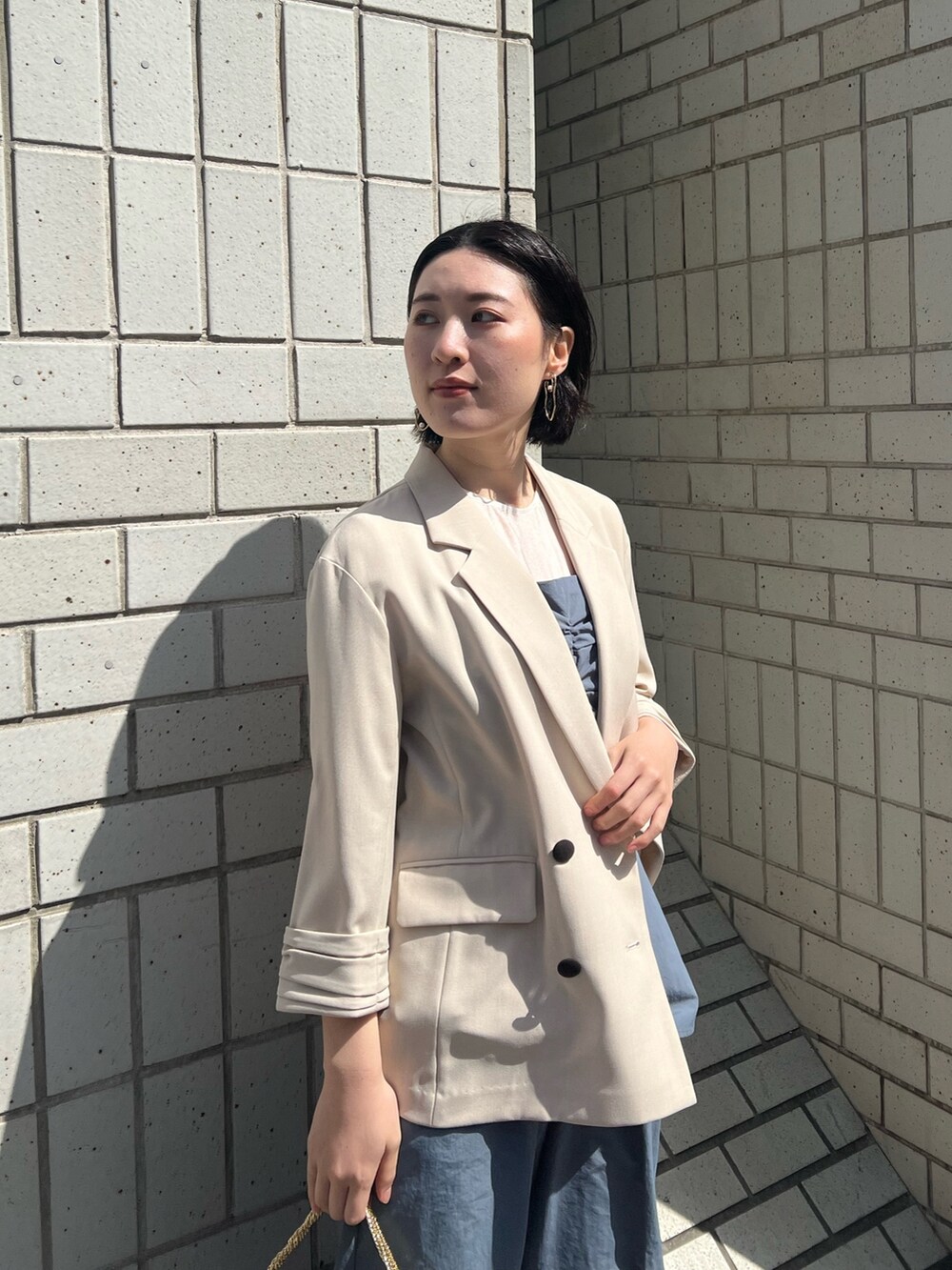 ゴールド系のパンプス、ゴールド系のハンドバッグ、ブルー系のパンツドレスを着用したレディースの春コーディネートの2枚目の写真