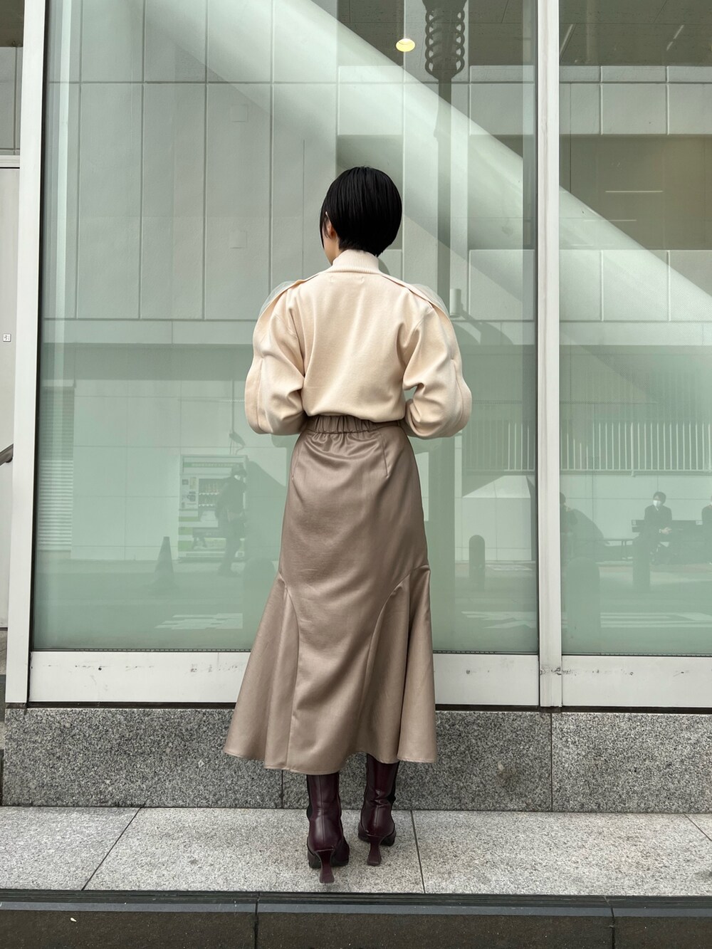 レッド系のブーツ、ベージュ系のスカート、ホワイト系のニット/セーターを着用したレディースの冬コーディネートの3枚目の写真