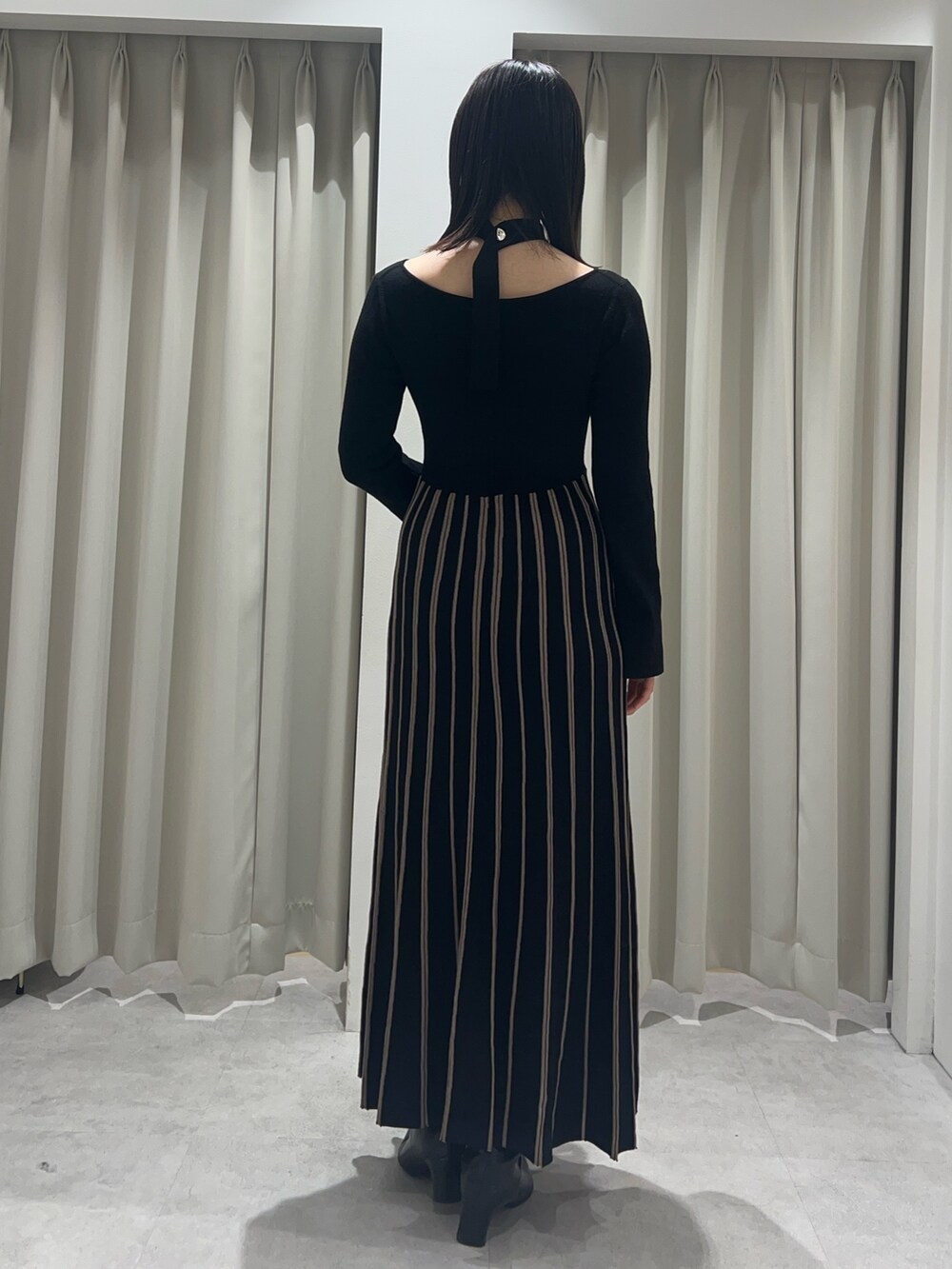 ブラック系のワンピース、ブラック系のブーツを着用したレディースの秋コーディネートの3枚目の写真