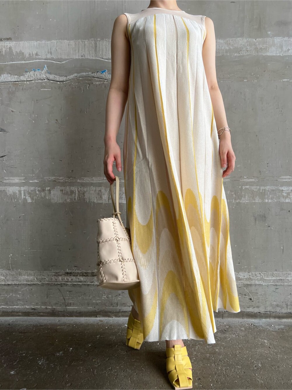 イエロー系のサンダル、イエロー系のワンピース、シルバー系のピアス（両耳用）を着用したレディースの夏コーディネートの4枚目の写真