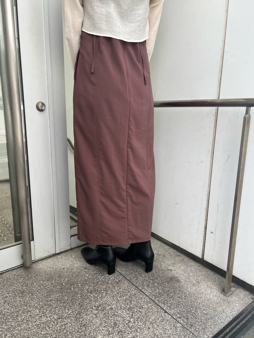 ブラック系のショルダーバッグ、ブラウン系のワンピース、ブラック系のブーツを着用したレディースの秋コーディネートの7枚目の写真