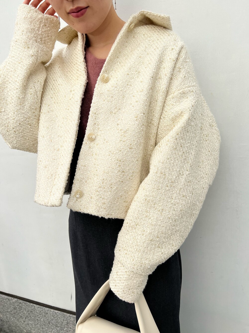 ホワイト系のハンドバッグ、グレー系のスカート、ベージュ系のブーツを着用したレディースの秋コーディネートの3枚目の写真