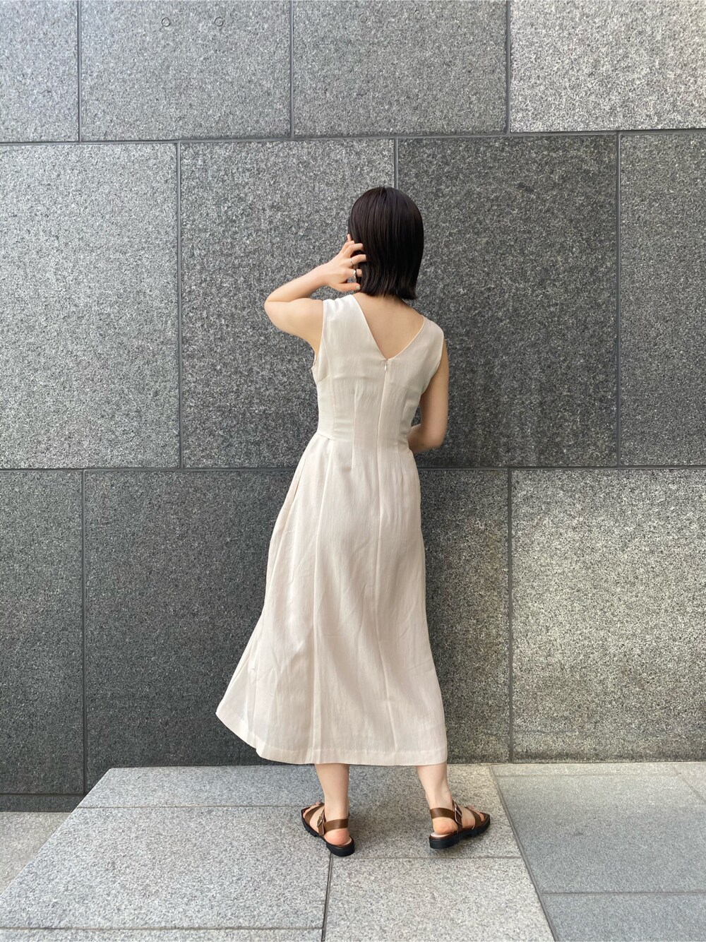 ブルー系のデニムパンツ、ブラウン系のサンダル、ベージュ系のワンピースを着用したレディースの春コーディネートの6枚目の写真