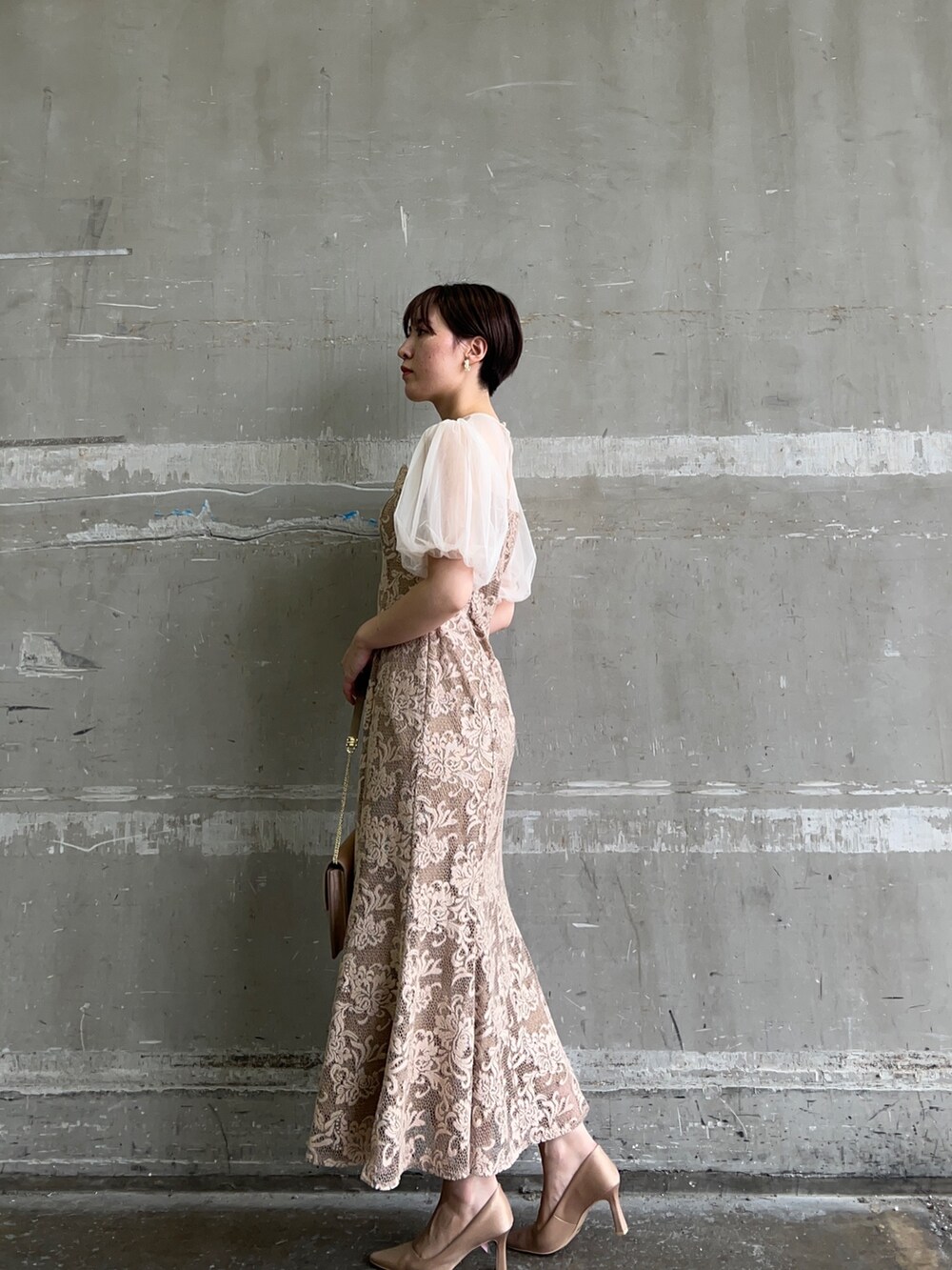 ベージュ系のドレス、ブラウン系のクラッチバッグ、ゴールド系のパンプスを着用したレディースの秋コーディネートの2枚目の写真