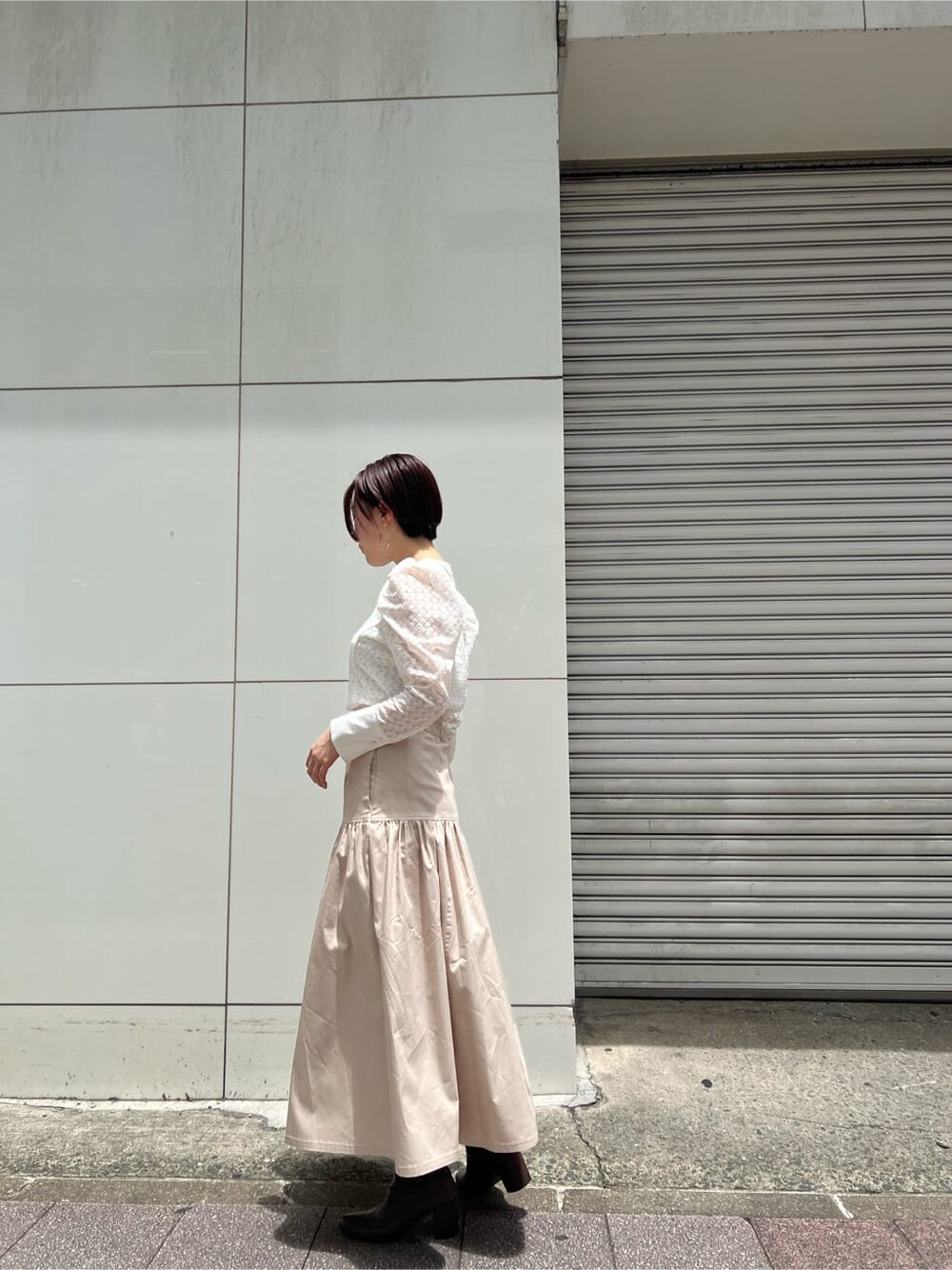 ベージュ系のスカート、ホワイト系のシャツ/ブラウス、シルバー系のピアス（両耳用）を着用したレディースの夏コーディネートの2枚目の写真