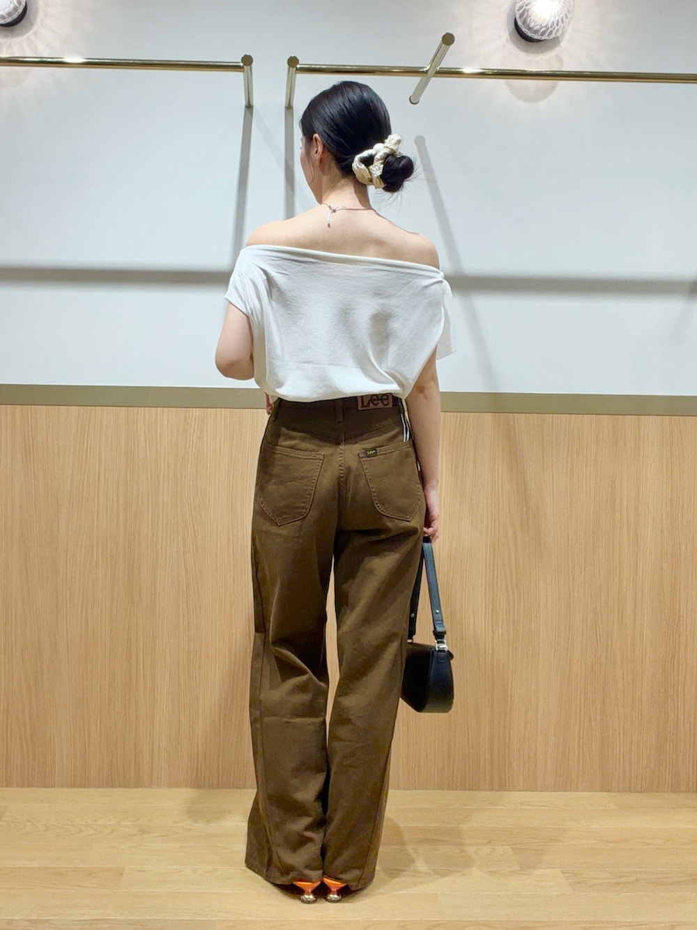 ブラウン系のデニムパンツ、オレンジ系のサンダル、ホワイト系のニット/セーターを着用したレディースの夏コーディネートの3枚目の写真