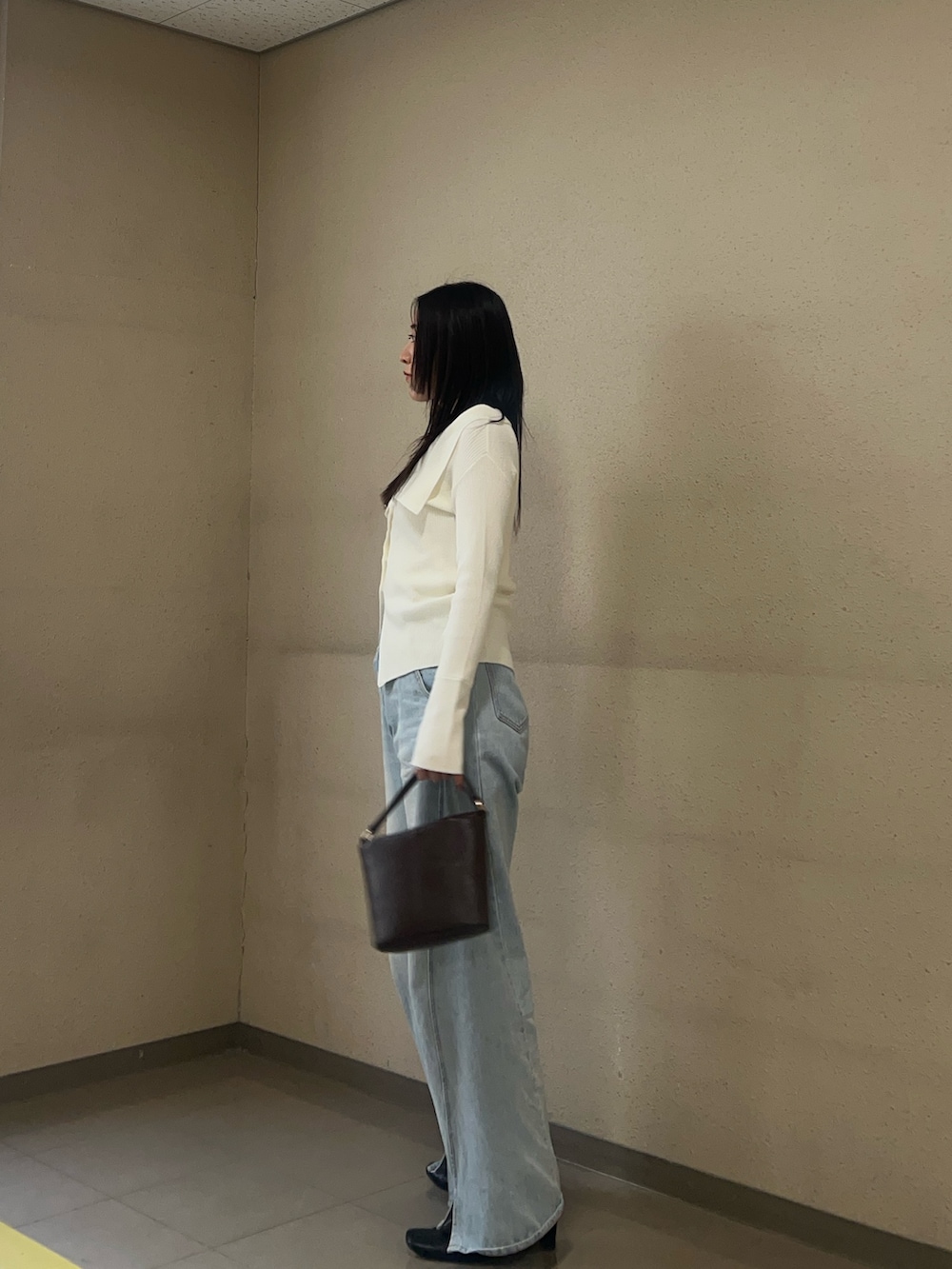 ホワイト系のアンサンブル、ブルー系のデニムパンツを着用したレディースの冬コーディネートの2枚目の写真