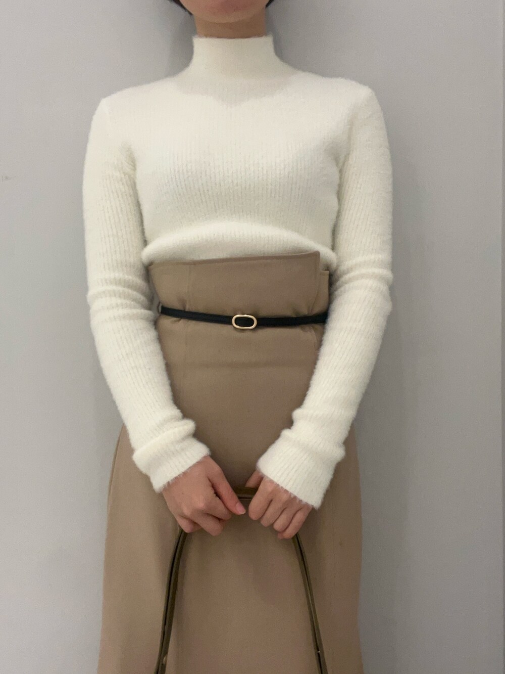 ベージュ系のブーツ、ブラウン系のショルダーバッグ、ベージュ系のスカートを着用したレディースの冬コーディネートの3枚目の写真