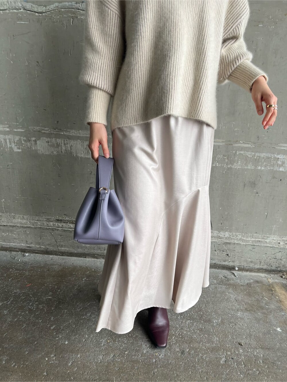 レッド系のブーツ、グレー系のスカート、パープル系のハンドバッグを着用したレディースの秋コーディネートの4枚目の写真