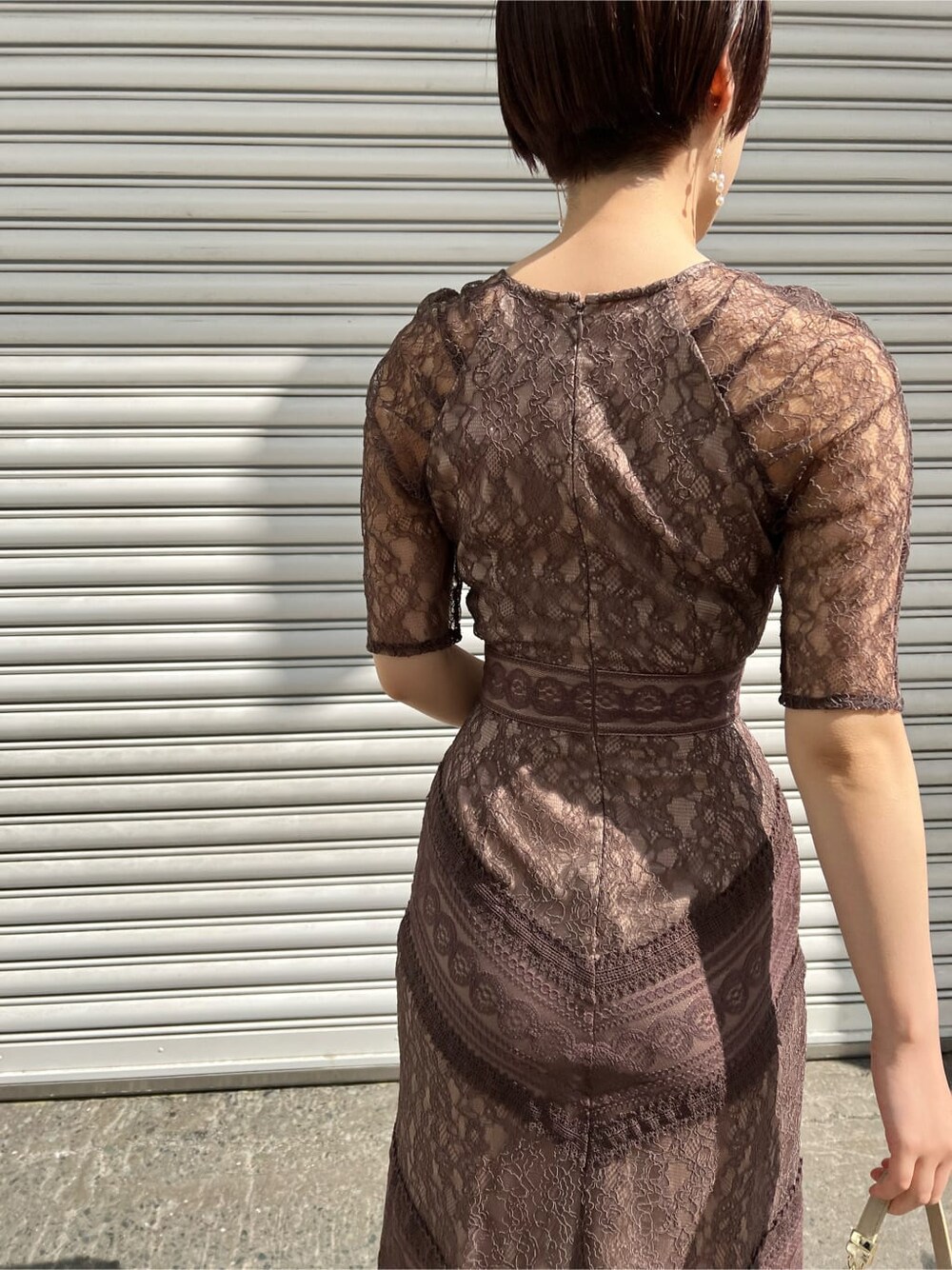 ホワイト系のノーカラーコート、ベージュ系のドレス、ベージュ系のクラッチバッグを着用したレディースの春コーディネートの5枚目の写真