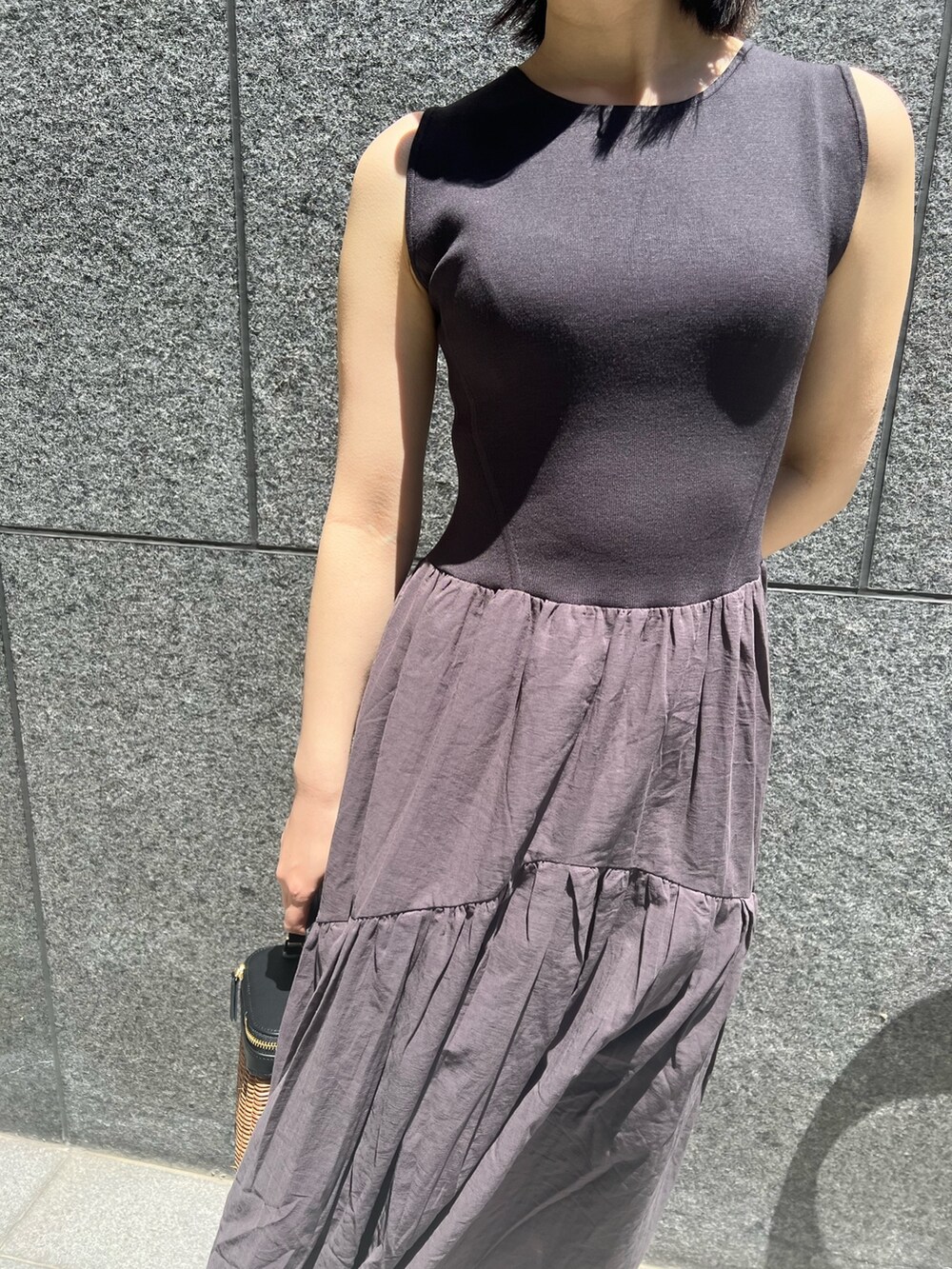 ブラック系のショルダーバッグ、ブラック系のサンダル、グレー系のワンピースを着用したレディースの春コーディネートの3枚目の写真