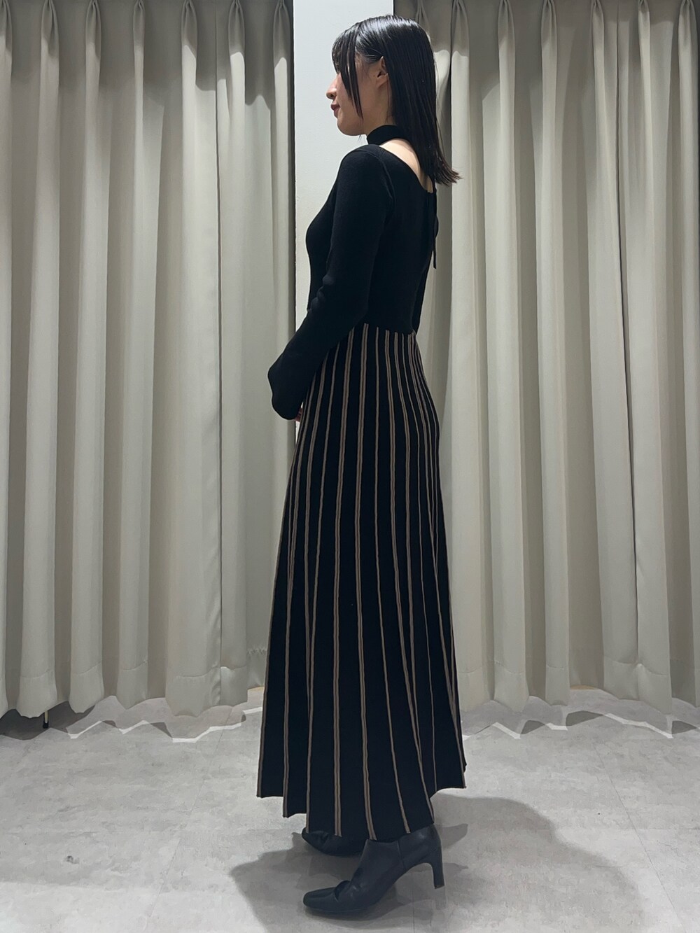 ブラック系のワンピース、ブラック系のブーツを着用したレディースの秋コーディネートの2枚目の写真