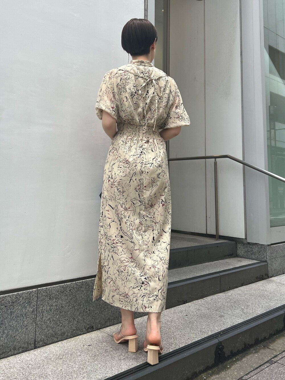 ブラック系のハンドバッグ、その他のサンダル、ベージュ系のワンピースを着用したレディースの夏コーディネートの2枚目の写真