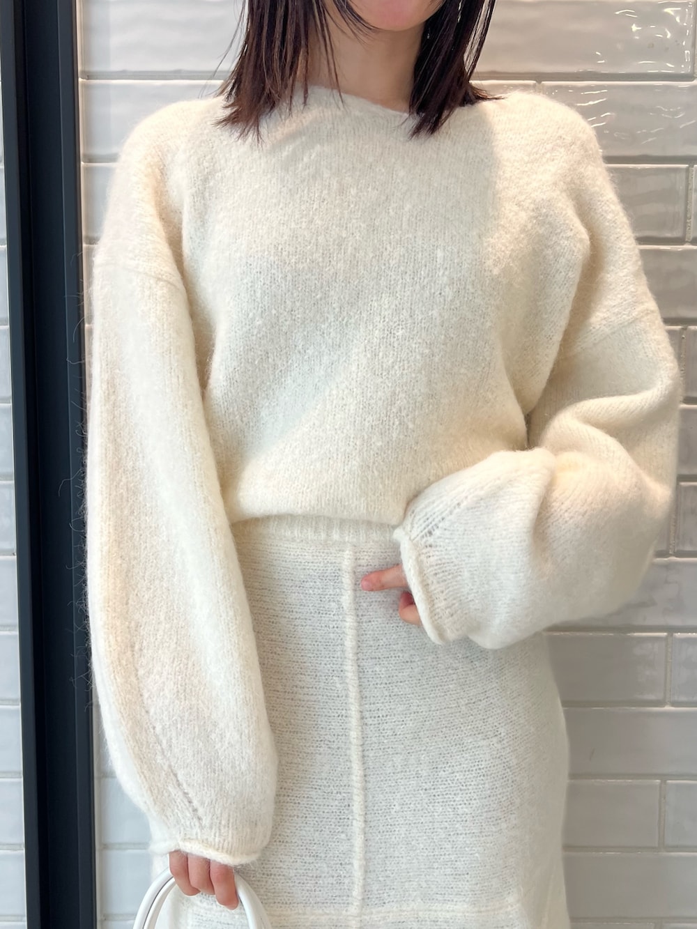 ホワイト系のスカート、ホワイト系のニット/セーター、ホワイト系のショルダーバッグを着用したレディースの秋コーディネートの4枚目の写真