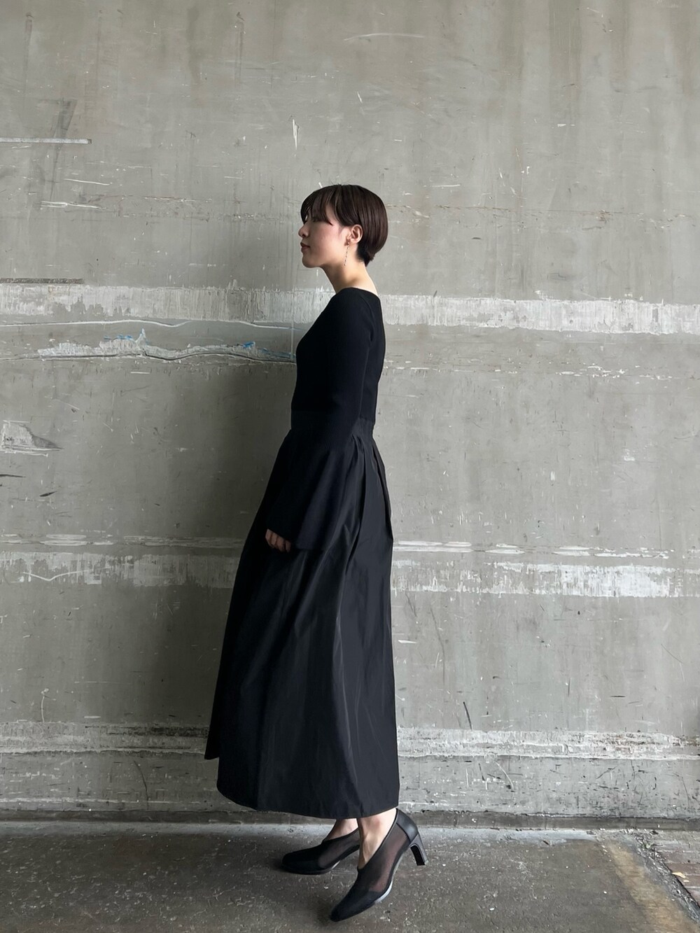 ホワイト系のハンドバッグ、ブラック系のワンピース、ブラック系のパンプスを着用したレディースの秋コーディネートの2枚目の写真