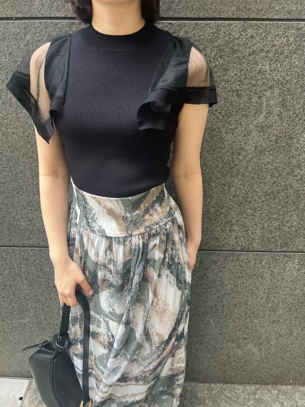 ブラック系のニット/セーター、グレー系のスカート、ブラック系のショルダーバッグを着用したレディースの春コーディネートの5枚目の写真