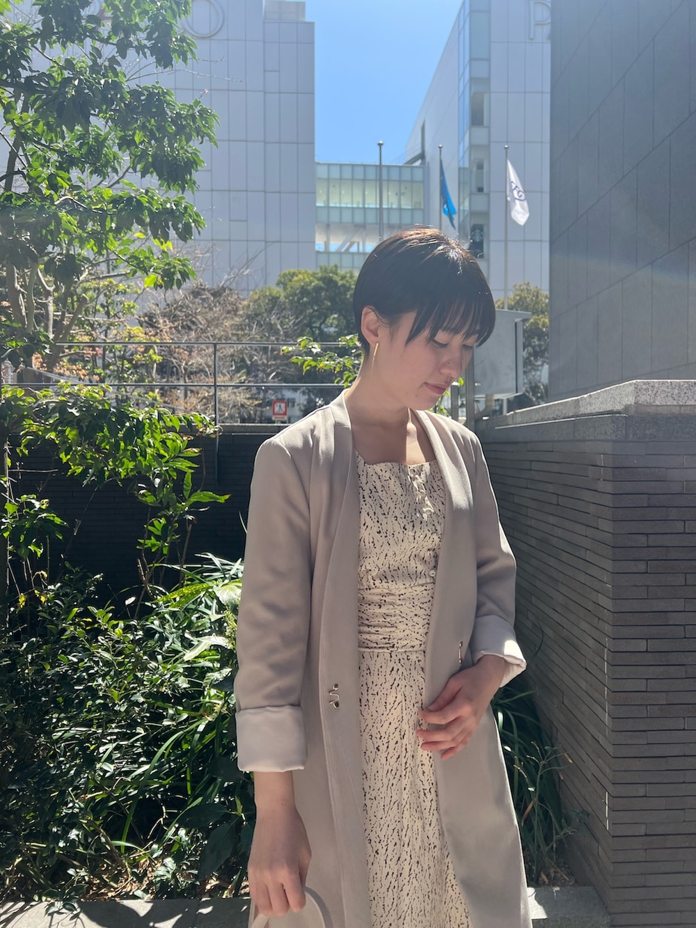 ホワイト系のハンドバッグ、ベージュ系のサンダル、ホワイト系のワンピースを着用したレディースの春コーディネートの3枚目の写真