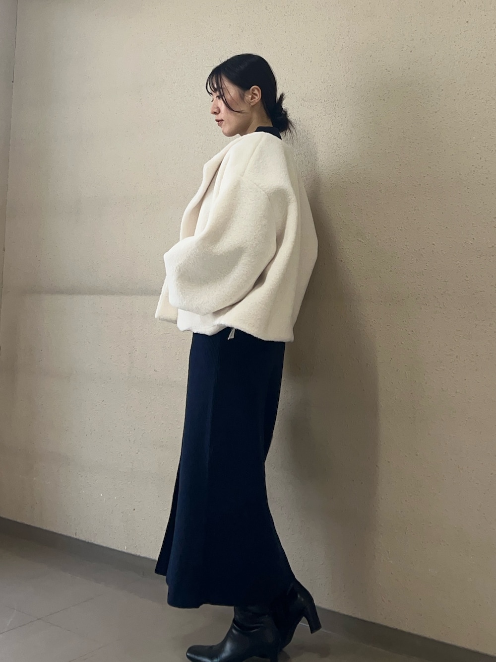 ホワイト系のブルゾン、ブルー系のワンピース、ブラック系のブーツを着用したレディースの秋コーディネートの2枚目の写真