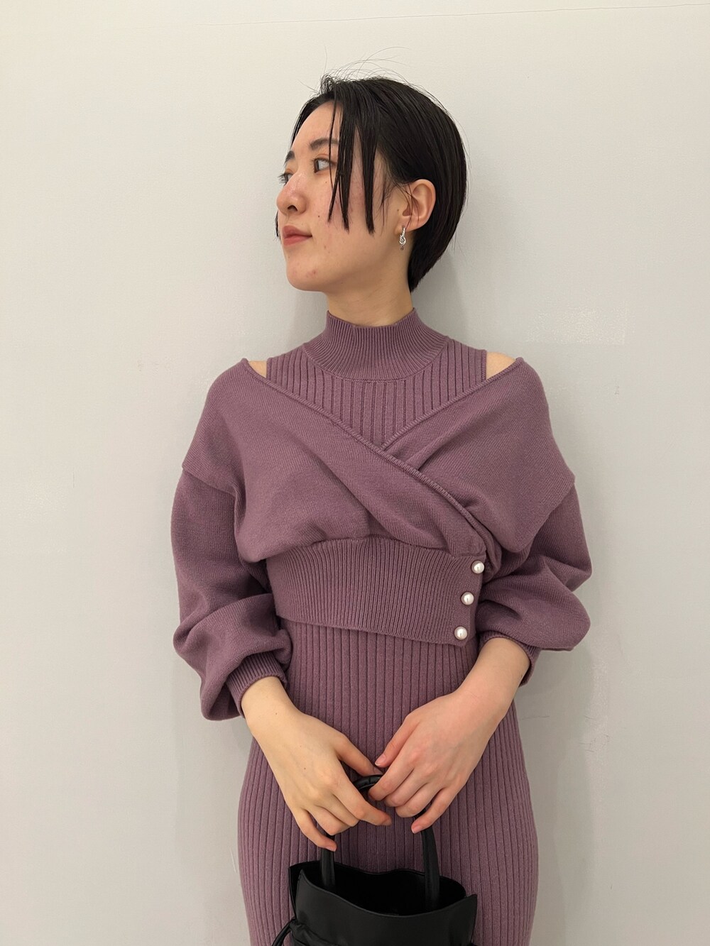 レッド系のブーツ、ブラック系のハンドバッグ、パープル系のワンピースを着用したレディースの冬コーディネートの4枚目の写真